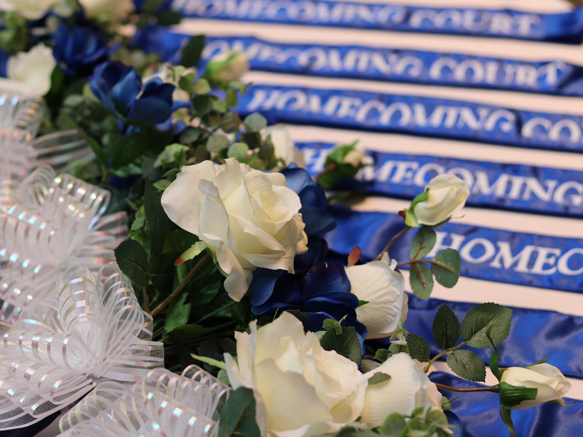 Blue and white flowers sit on a table next to a blue sash.