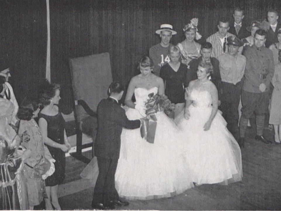 A woman wearing a white dress is presented as Homecoming queen in 1955