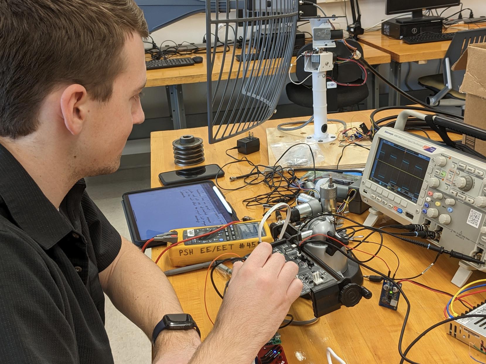 Person at a desk filled with electronic equipment