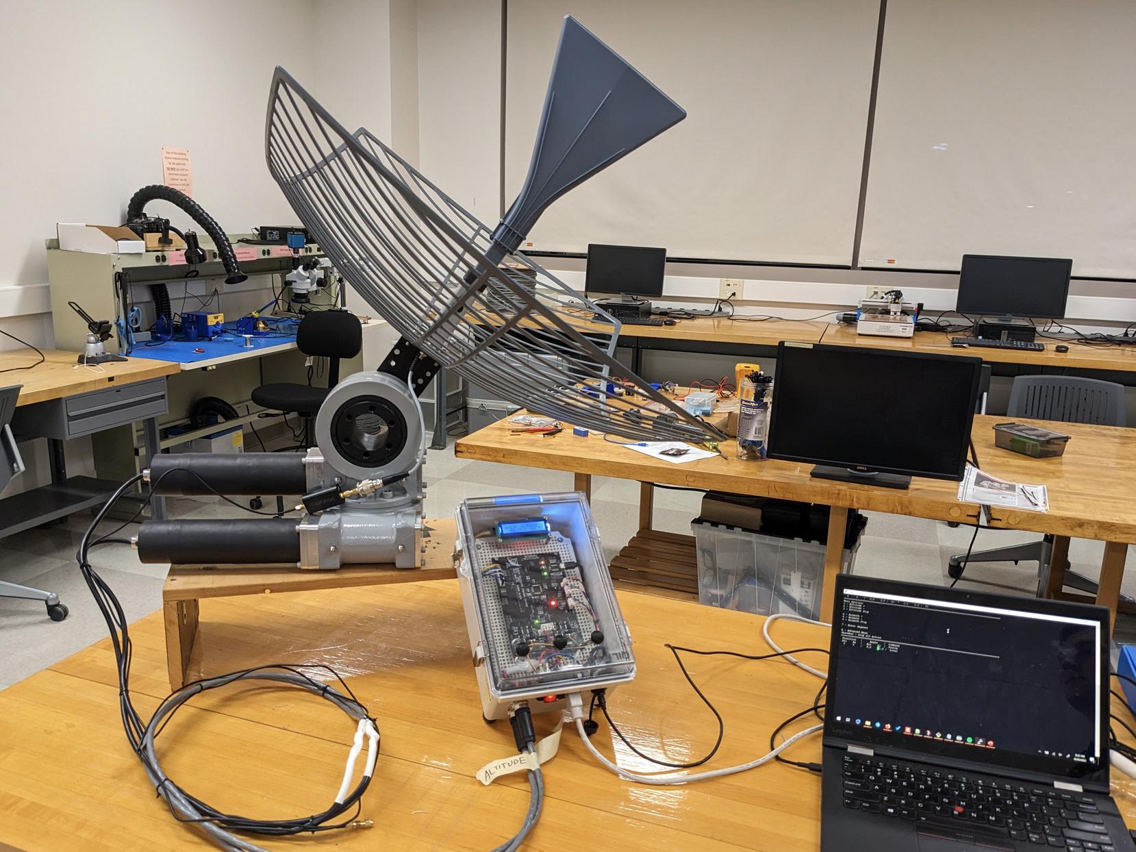 Photo of a dish antenna, control box and laptop