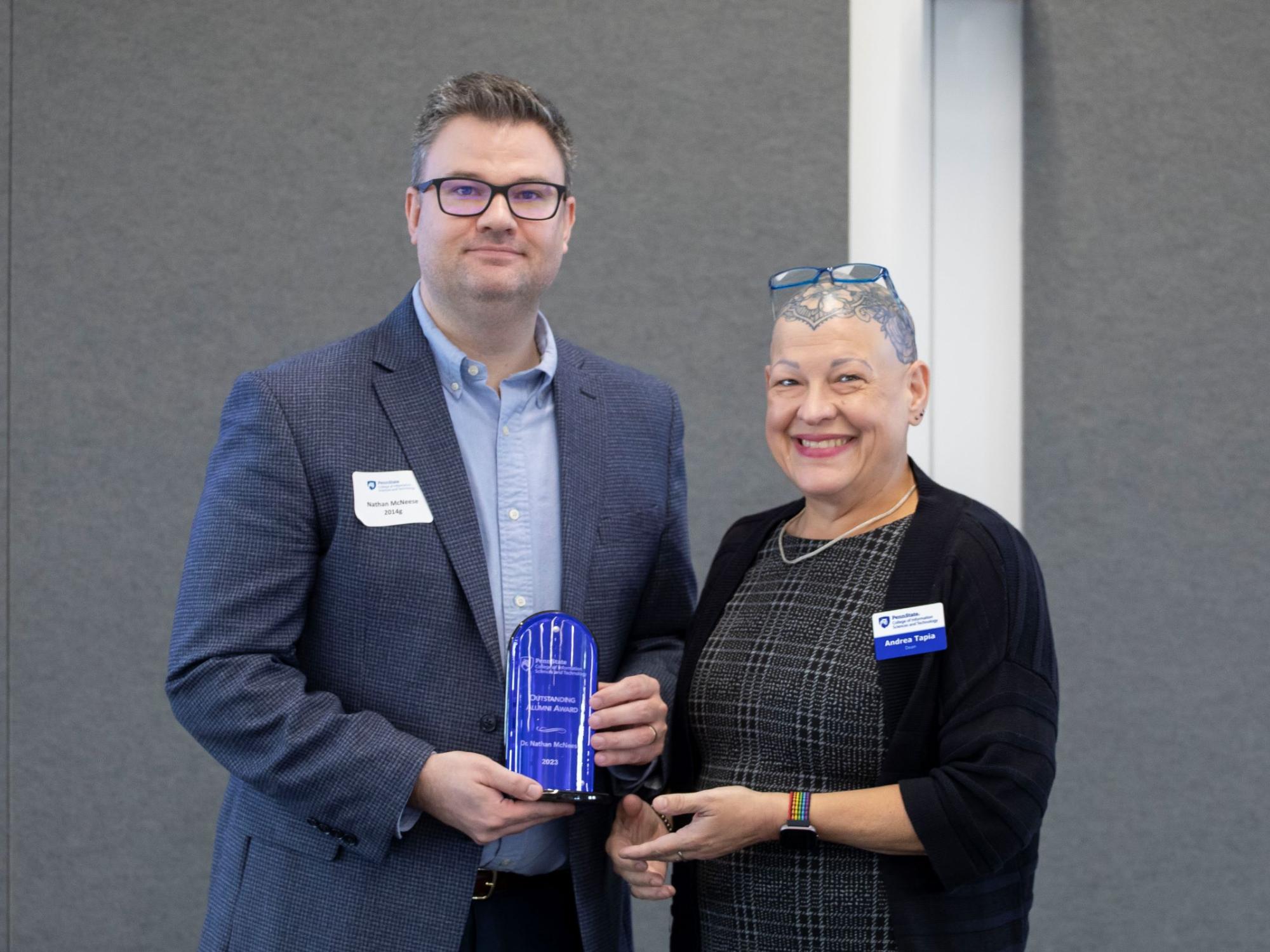 person wearing glasses accepts award from another