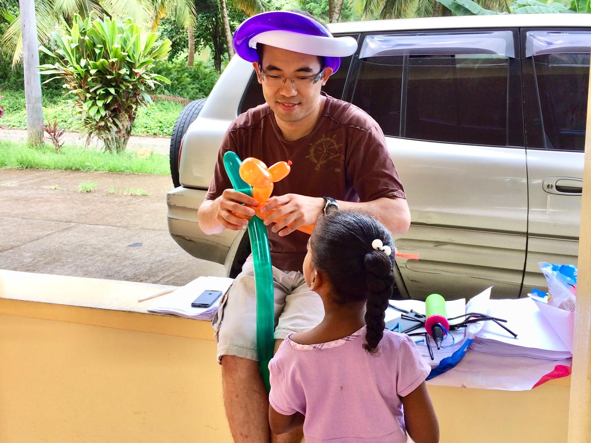 A person makes balloon animals in front of a child. 