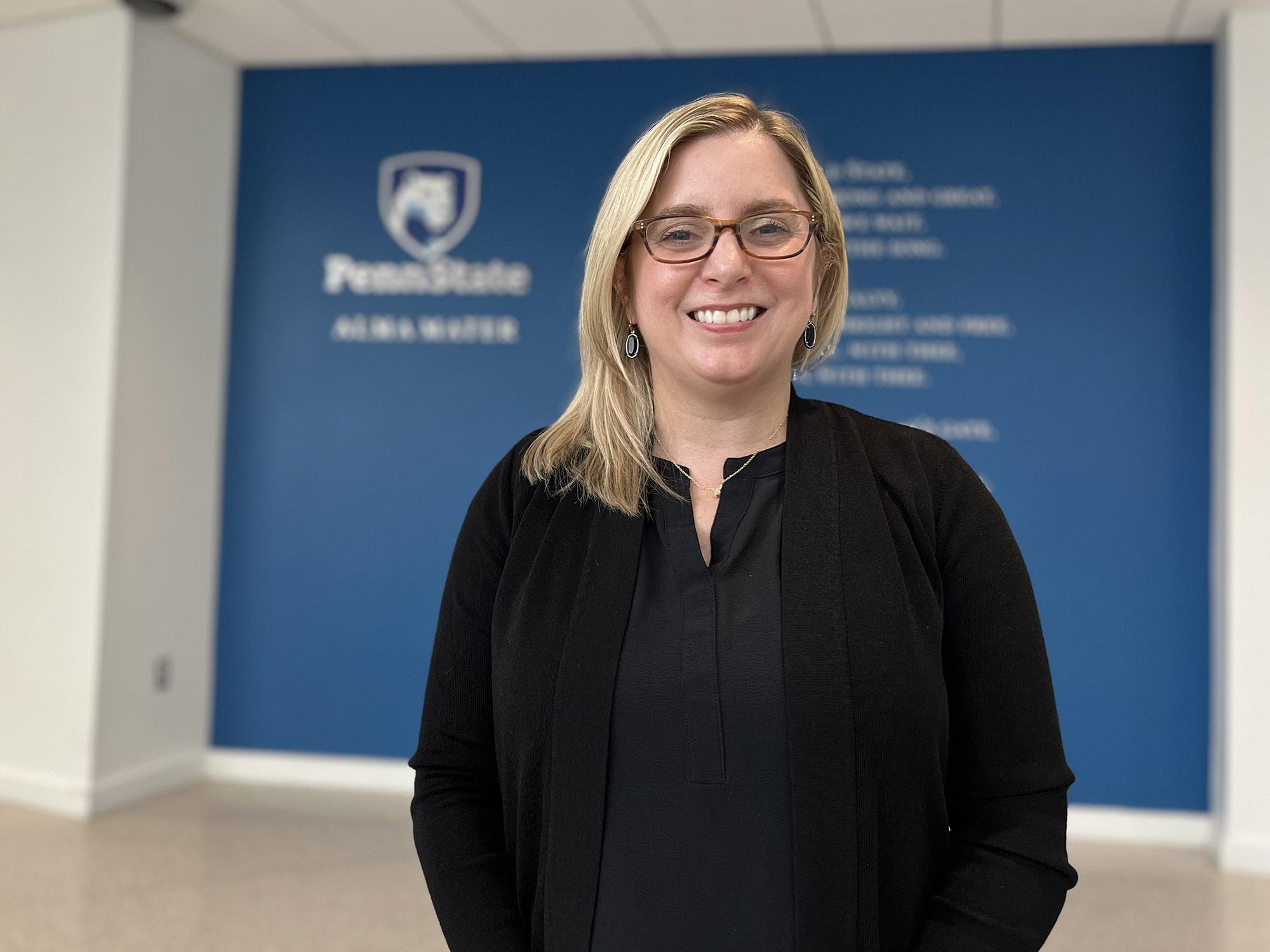 Laura Glotzbach stands in front of a wall that says Penn State Alma Mater and has the words in small type