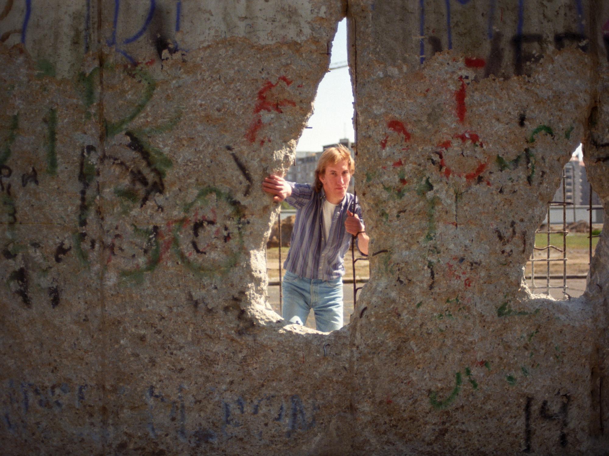 A man looking through a hole in the Berlin wall