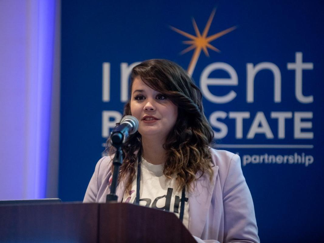 Mary Richardson speaks at podium in front of Invent Penn State signage during the Student Startup Showcase at the Invent Penn State Venture & IP Conference.