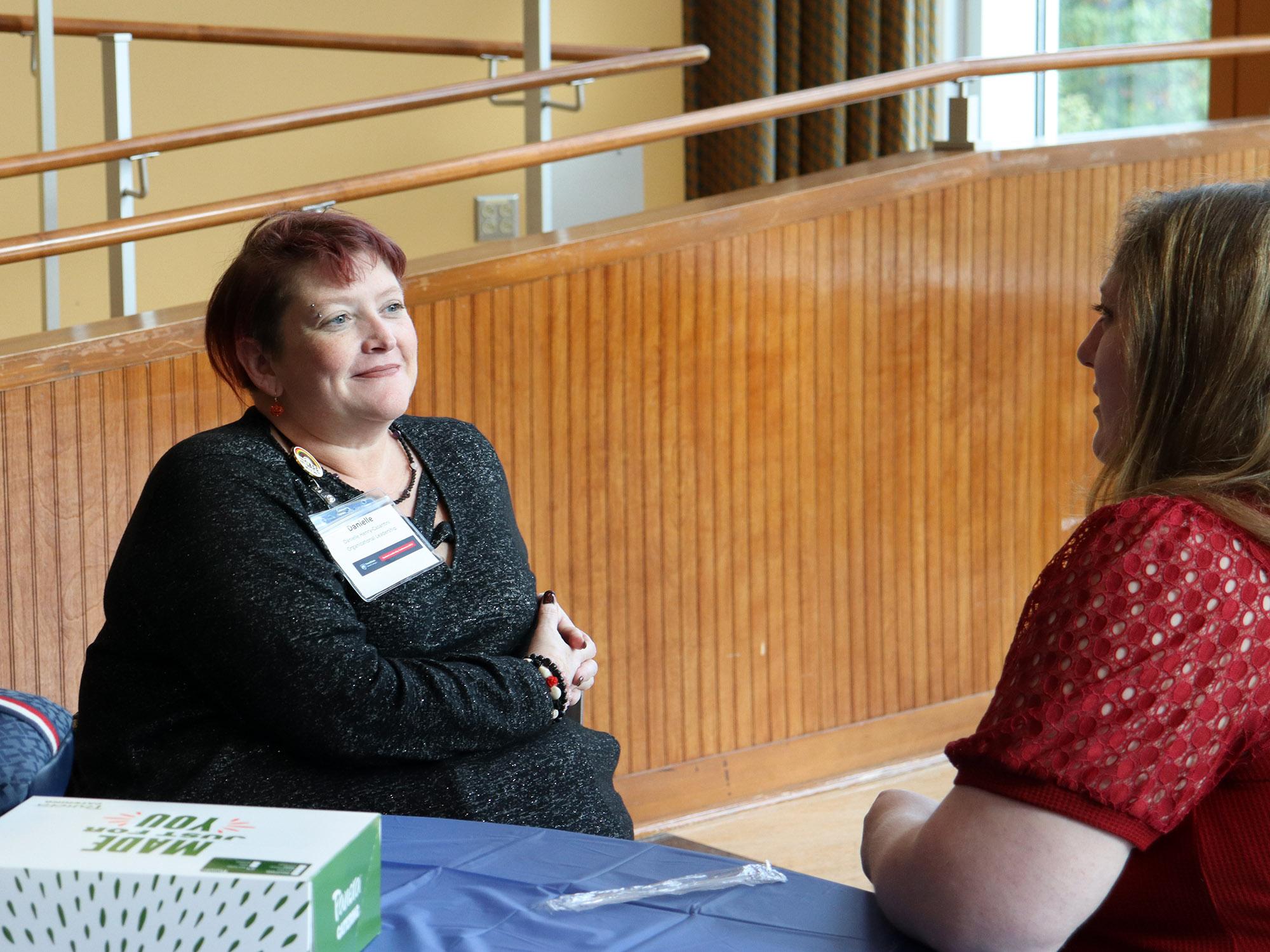 a student sitting talks to another one around a table