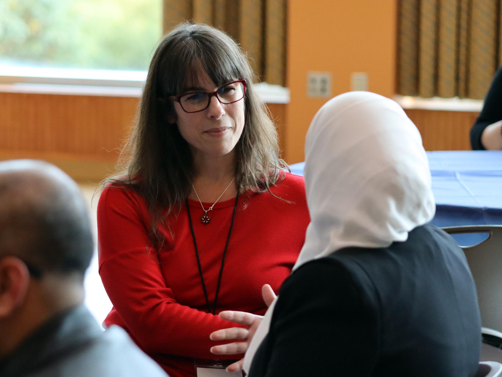 Laura Accardi sits at a table listening to another student