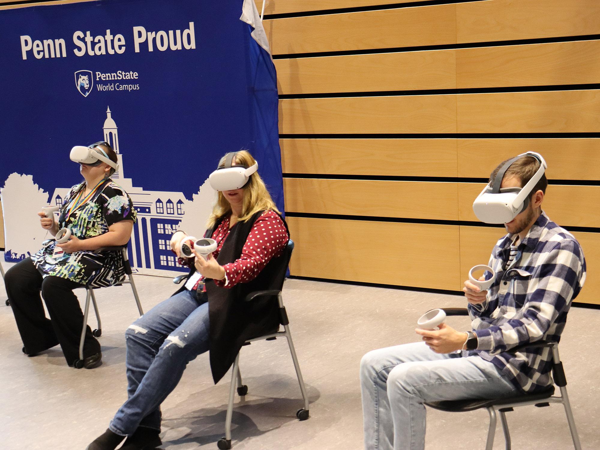 Three people sit on chairs with VR headsets and look at a device