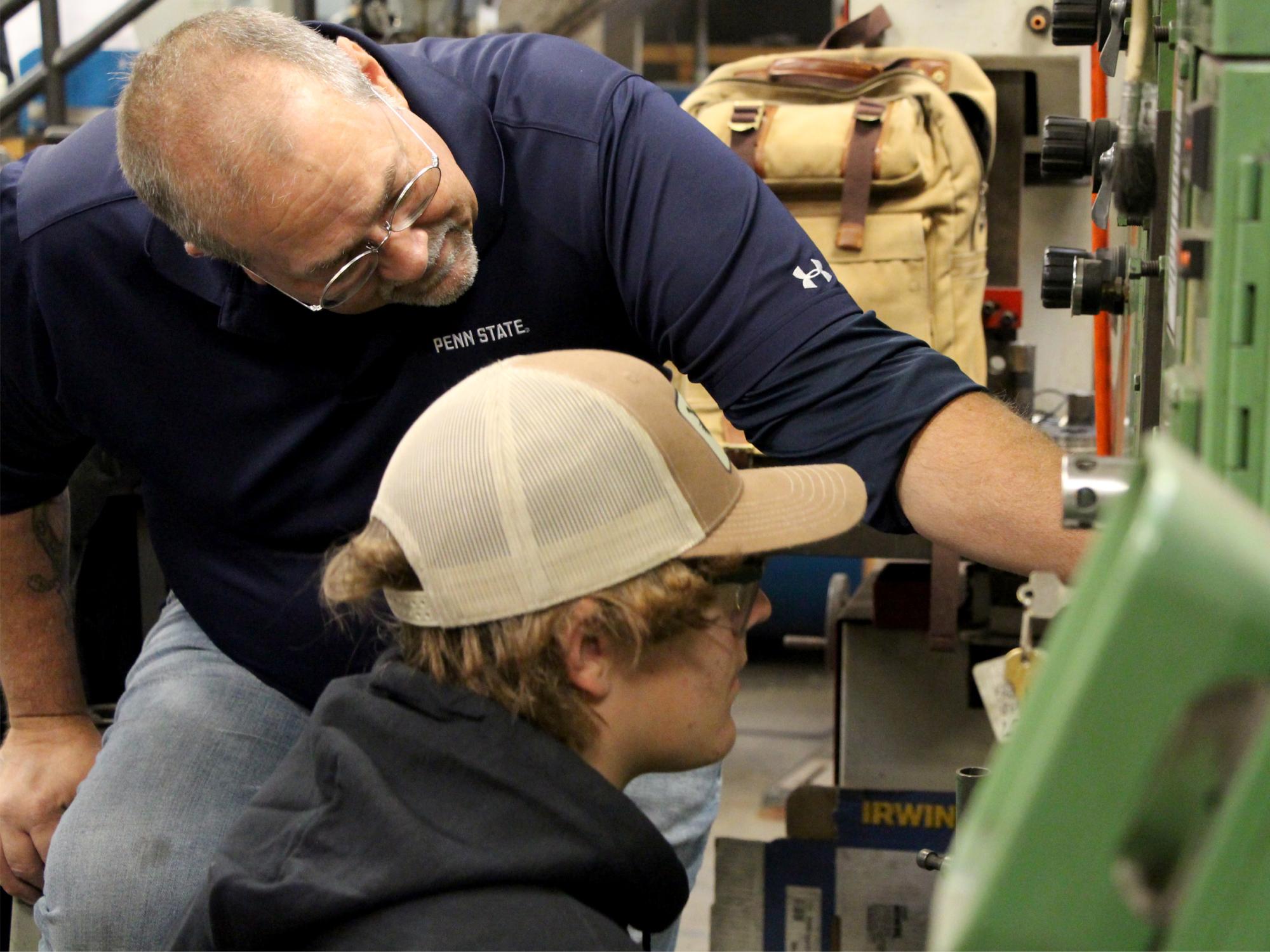 Under the watchful eye of George Schneider, top, Saint Marys Area High School student Justin Herbstritt works through set up procedures for a die set during the high school die setter training program.