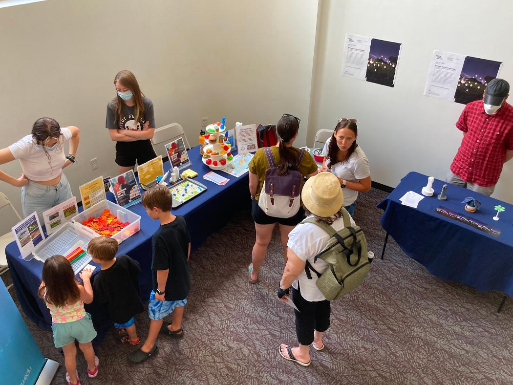 People mill around a reception with information tables at the Woskob Gallery
