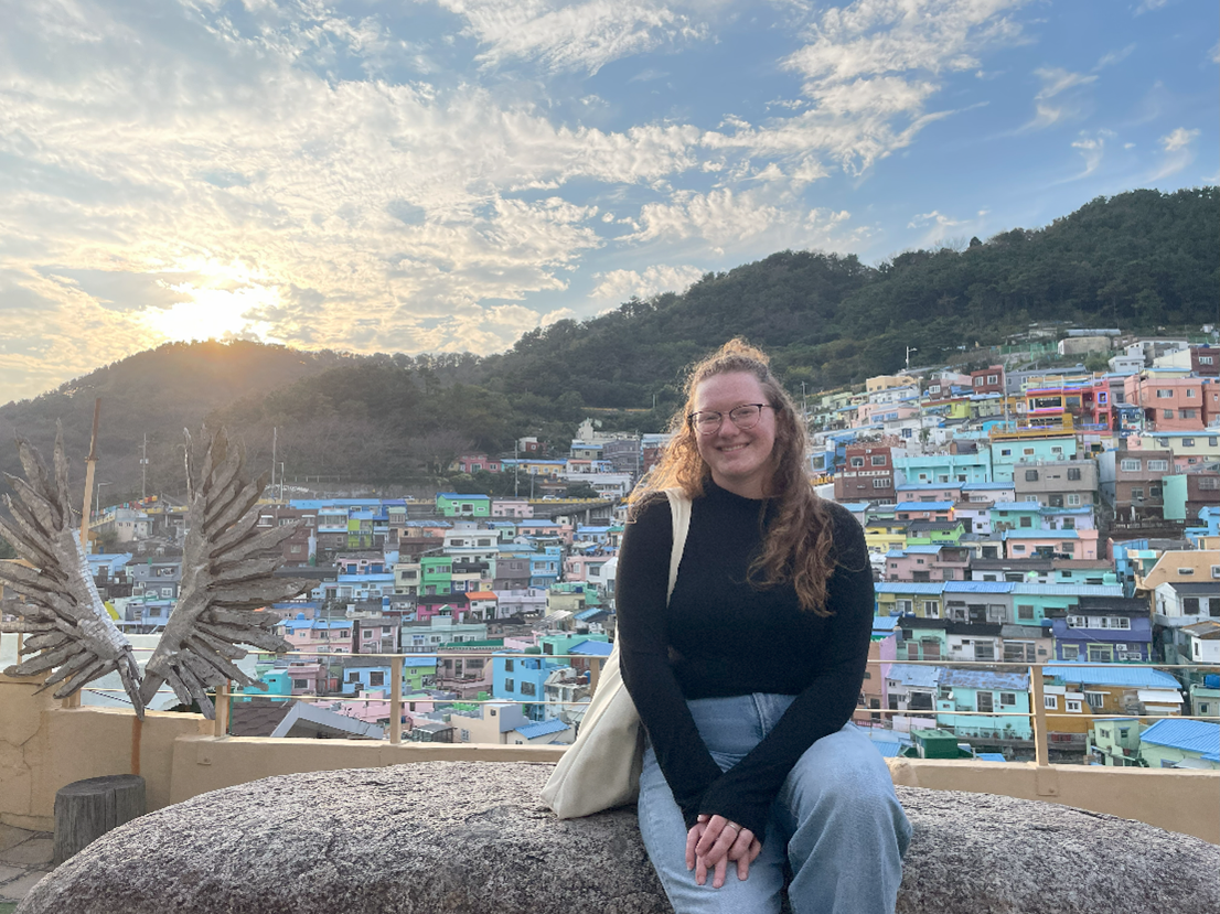 A woman sitting in front of a hillside full of colorful houses