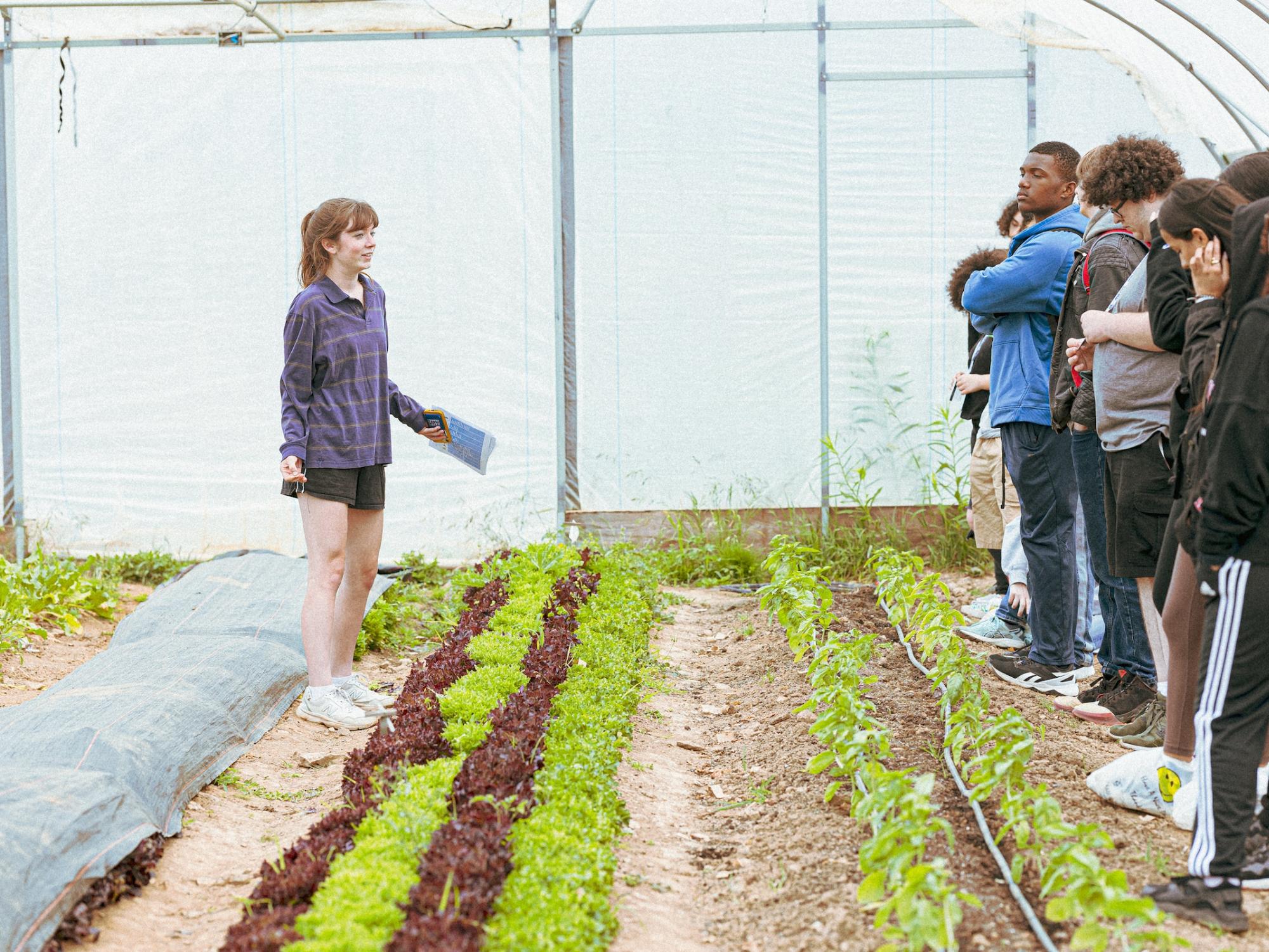 Vancie Peacock addressing group of students while standing in greenhouse