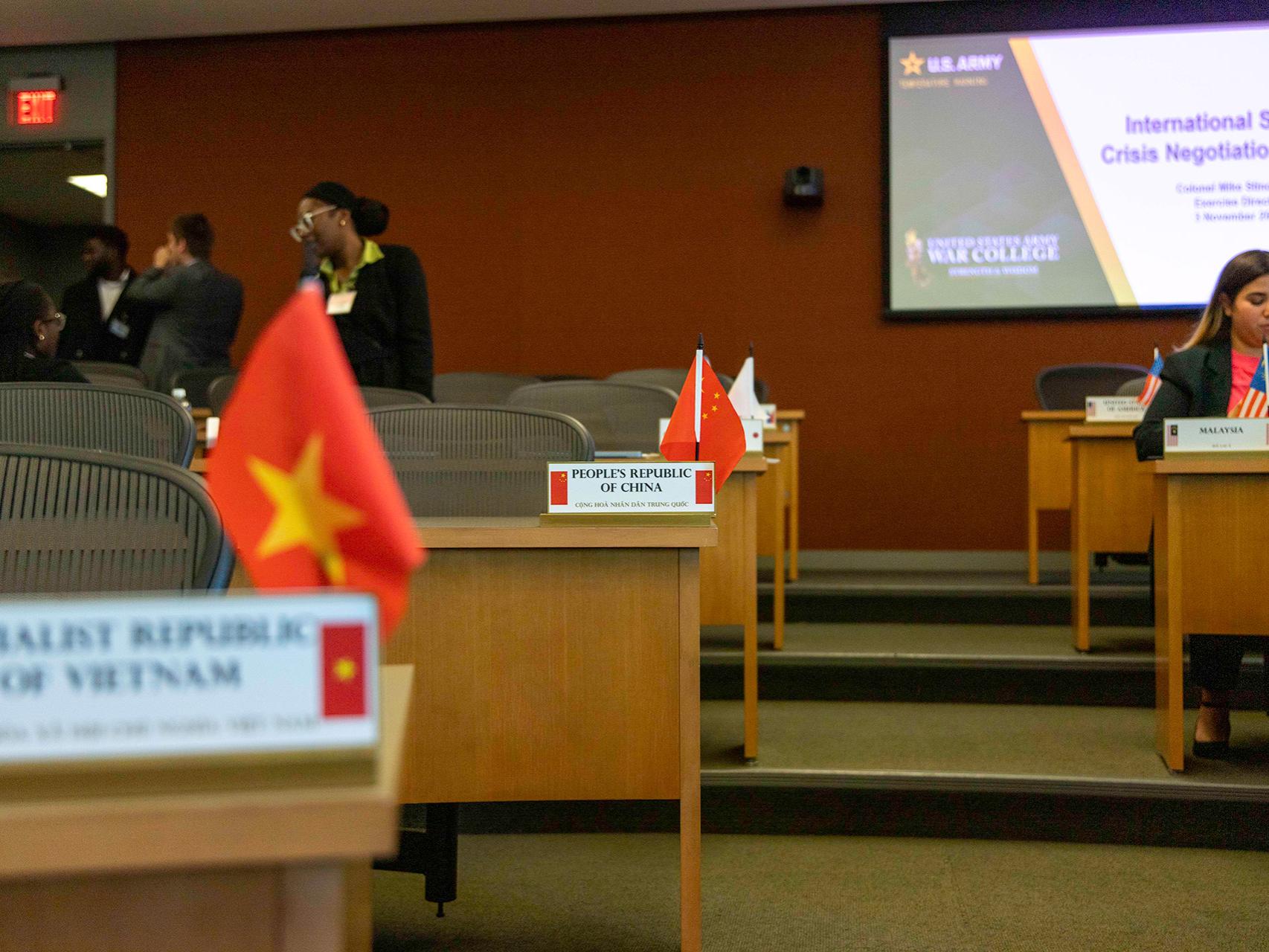 Country flags and placards marking the delegate sections for each country at the opening plenary session of the USAWC crisis simulation.