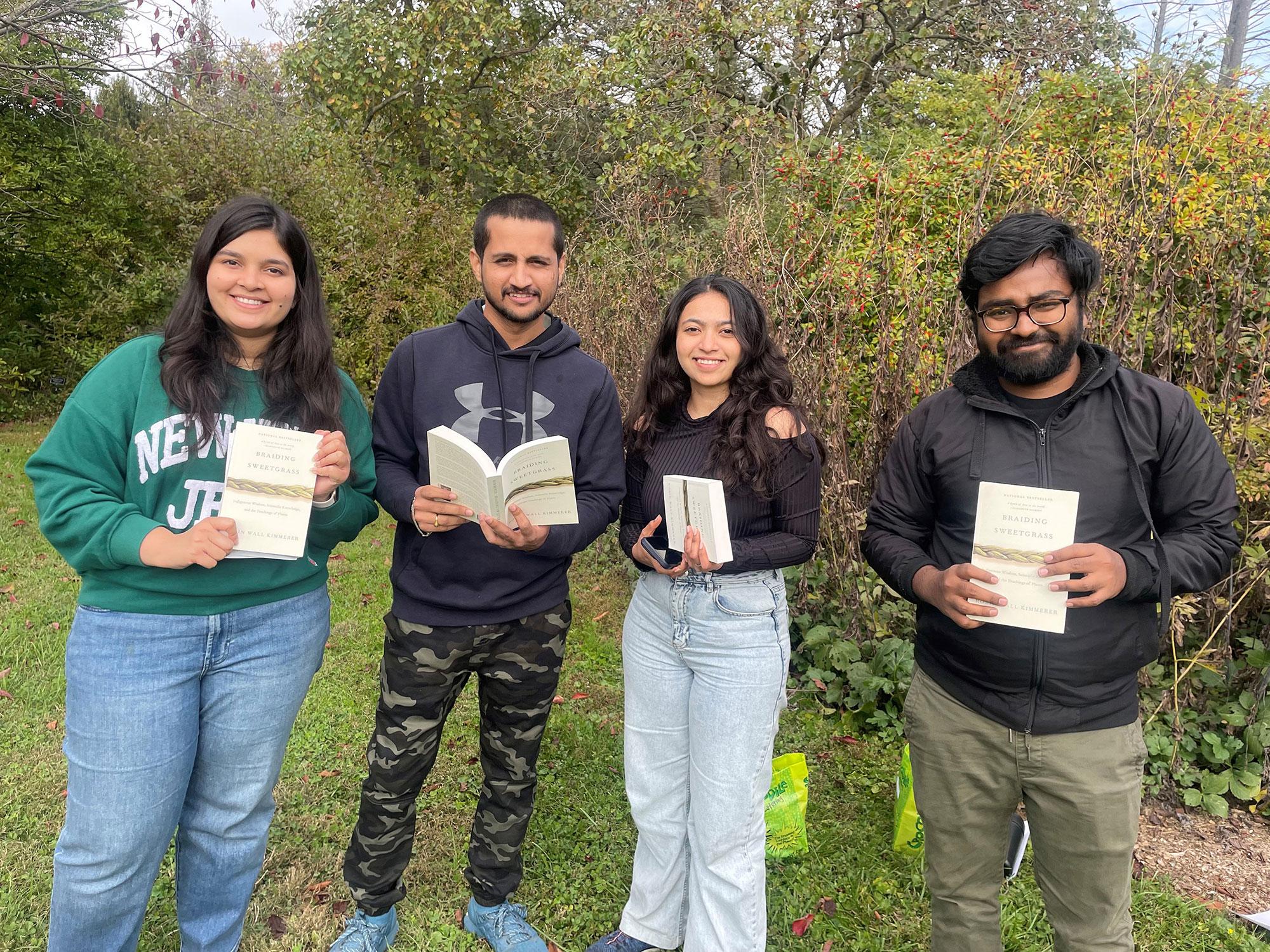 Four students holding books outside