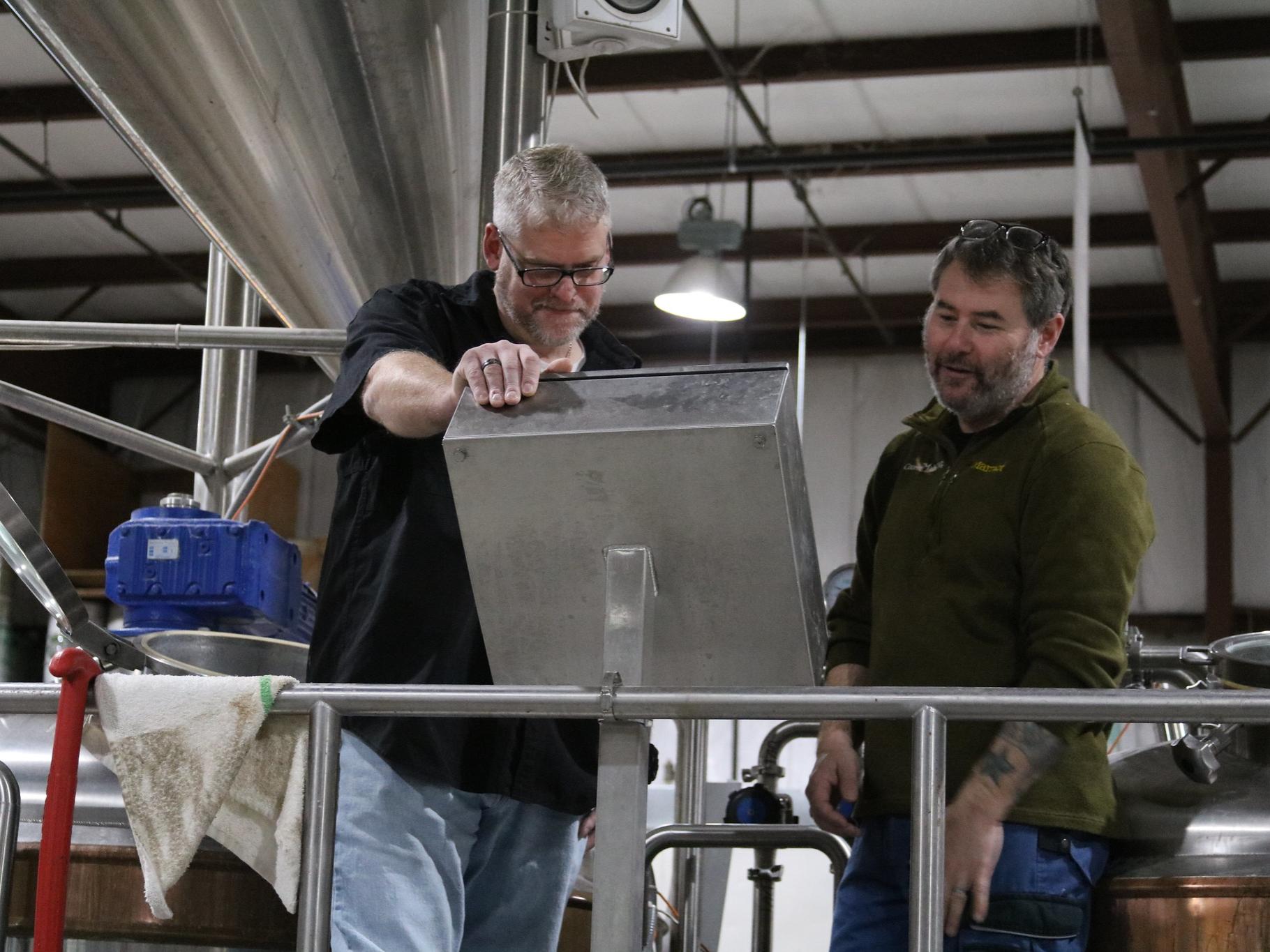 Two men looking thoughtfully at a screen in brewery