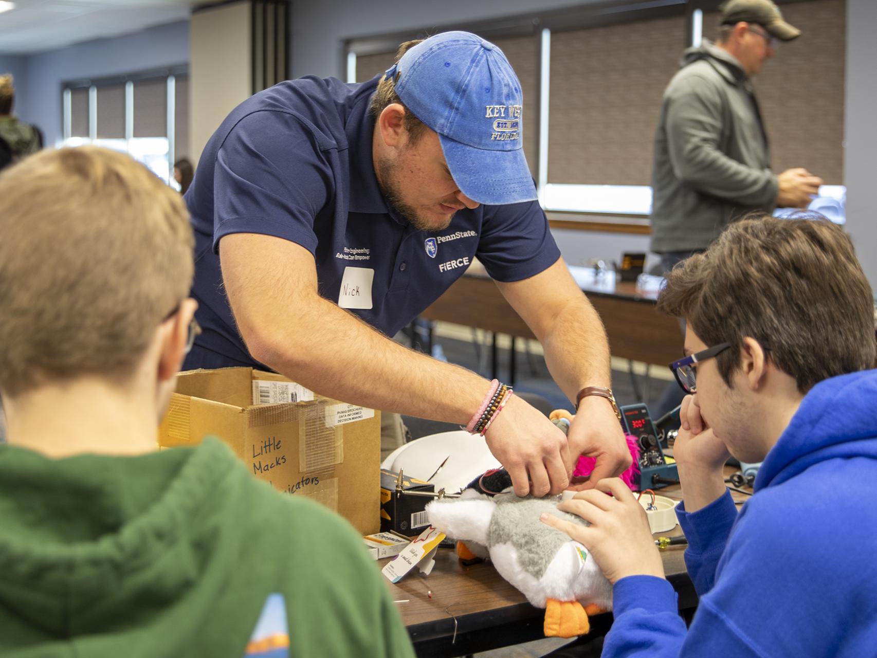 Penn State Berks student Nick Hall helps a high school solder the mechanics of a new button.