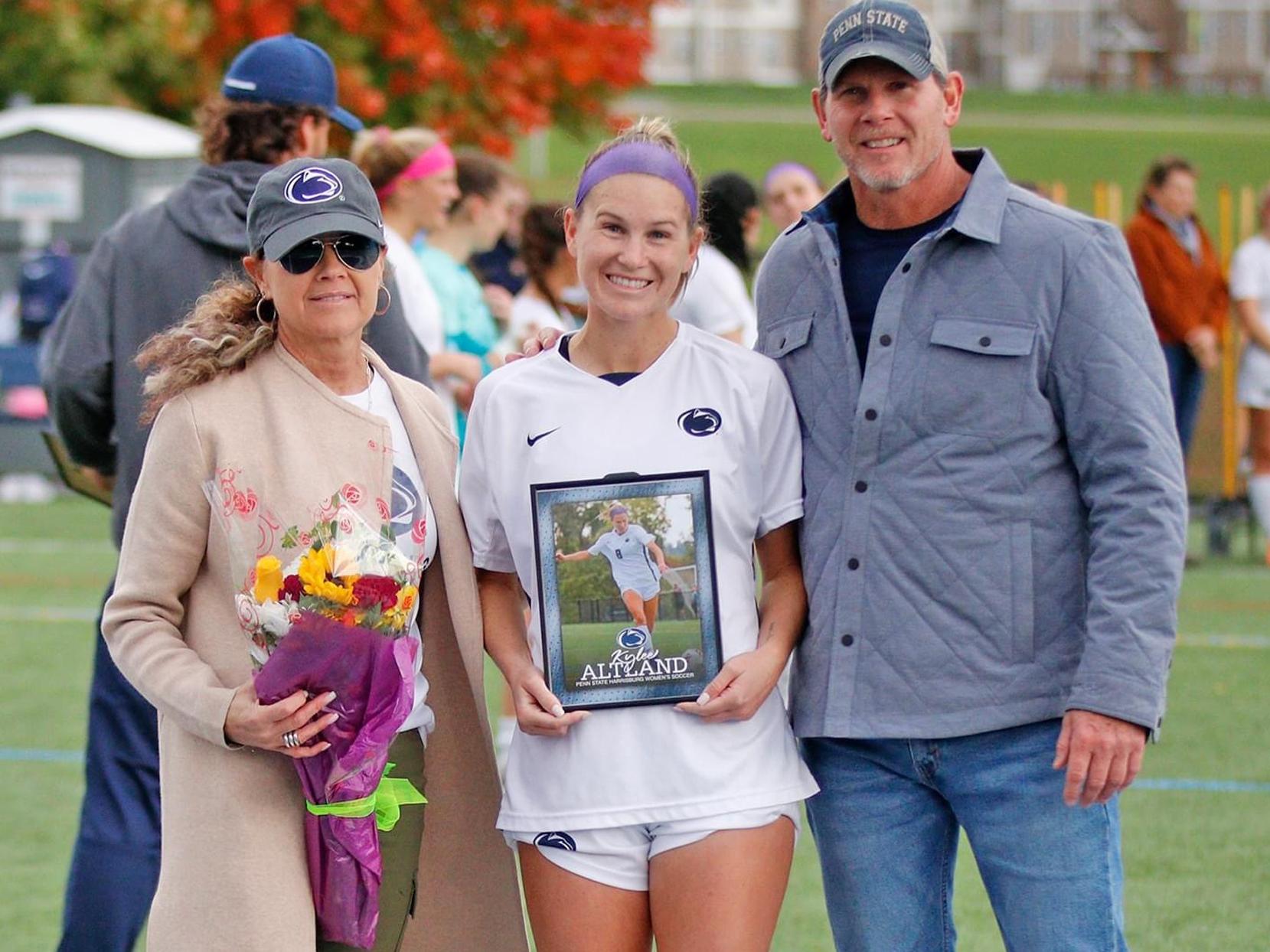 Kylee Altand standing between her mother (left) and father (right)