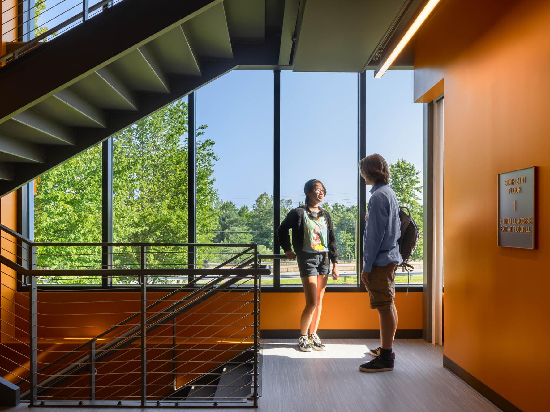 Two students talk on a stairway landing in Penn State Behrend's Federal House.