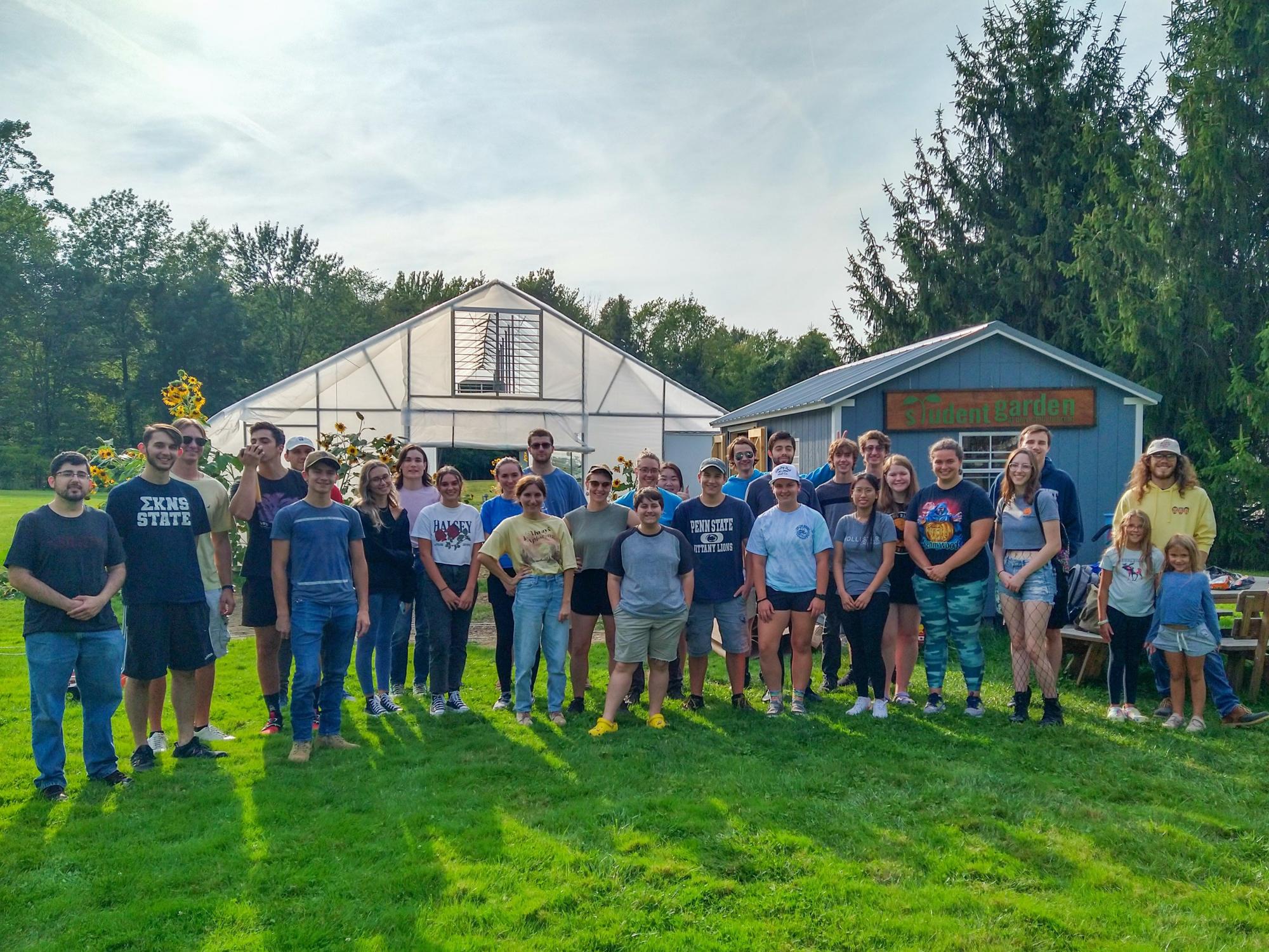 A large group of students stands in front of the high tunnel at Penn State Behrend.