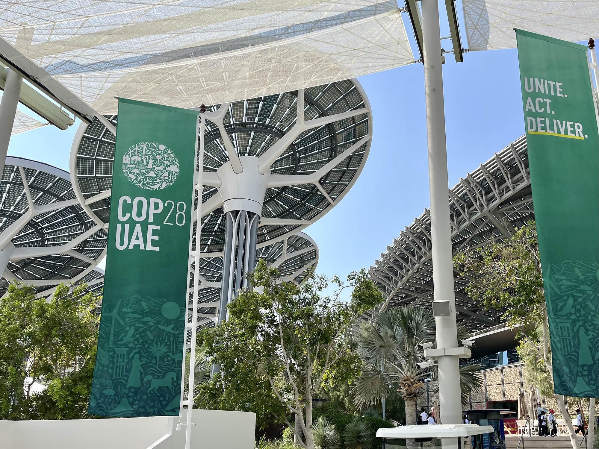 A COP28 UAE banner is shown hanging from an overhang