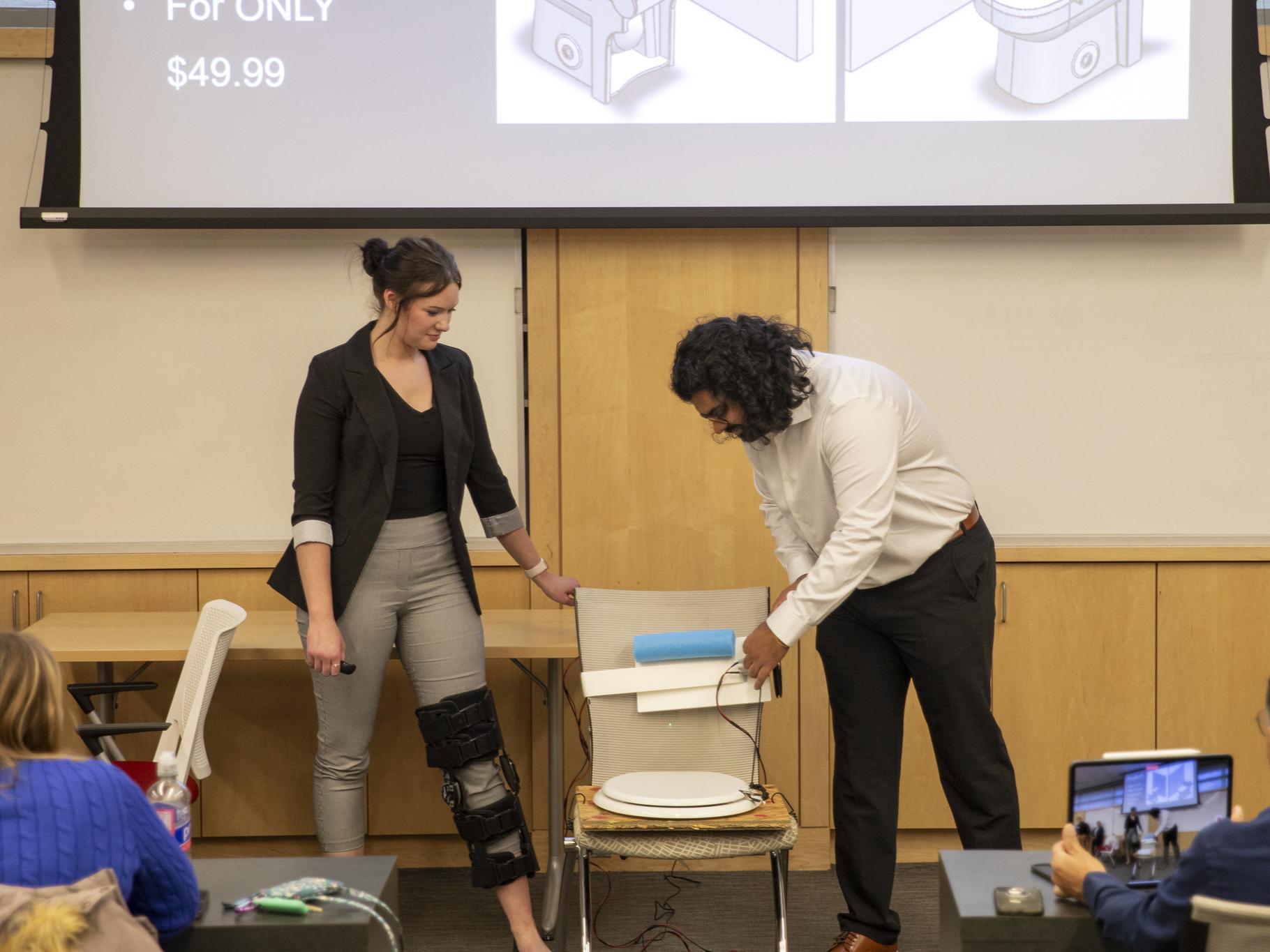 Female and male student present adaptive toilet lid opener 
