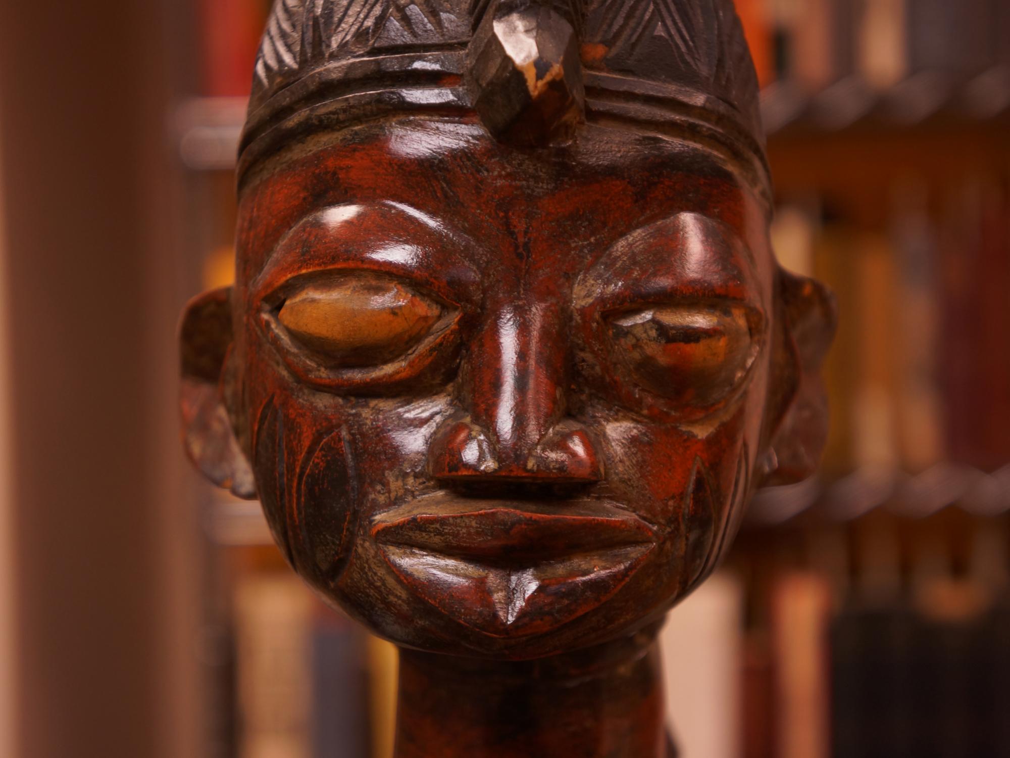 A close-up view of a statue of a person with large eyes and a headpiece.
