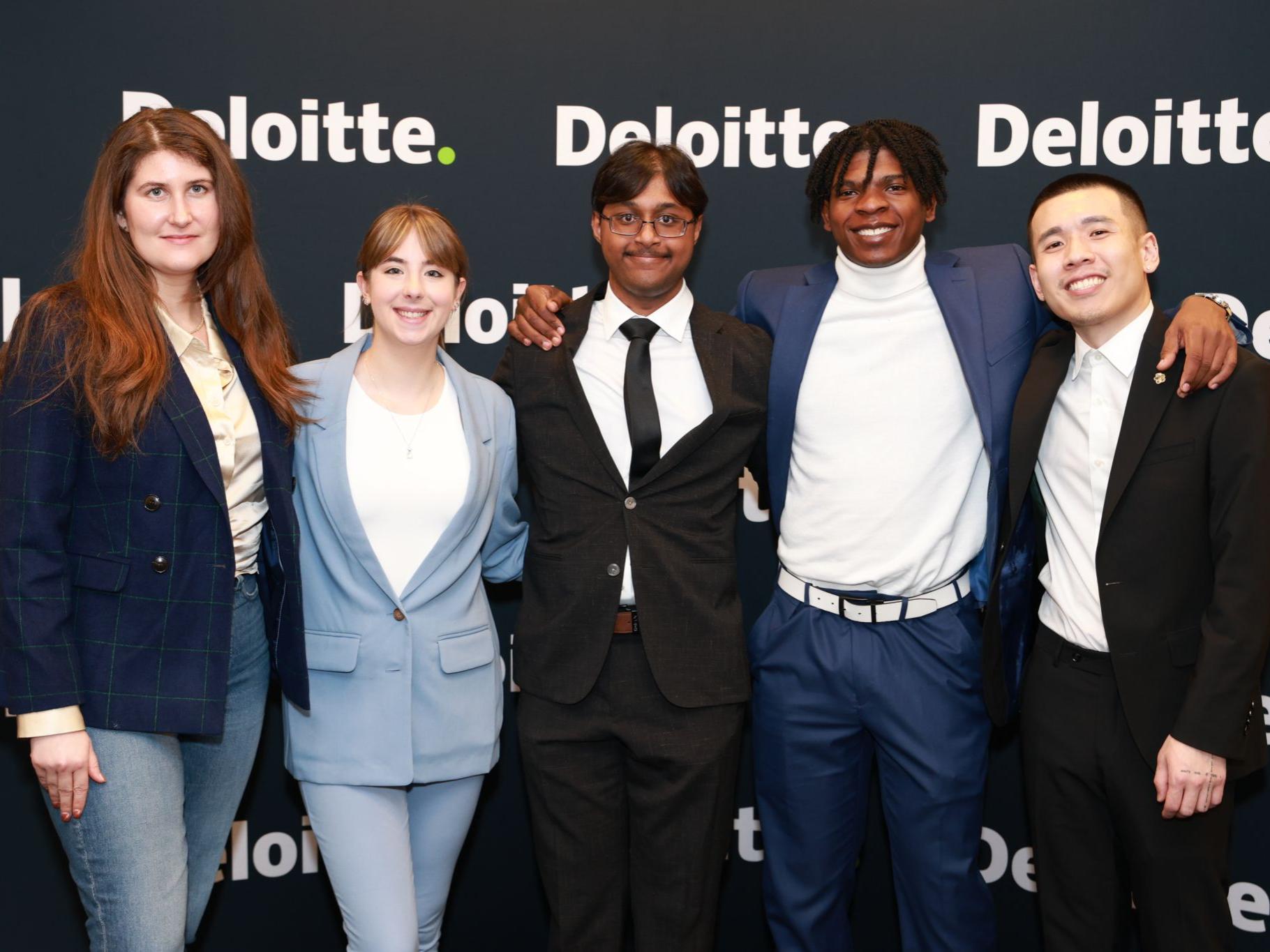 group of people in business attire pose in front of company logo