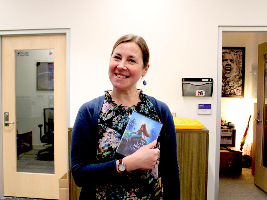 Diversity, Equity and Inclusion Coordinator Emily Glodzik shows off her borrowed DVD, "The Little Mermaid."