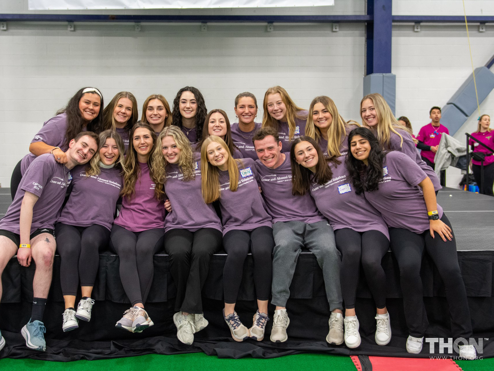 Two rows of students wearing purple shirts. Julia Jakuboski sits third from left in the first row with the rest of her alumni engagement committee.