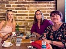 A group of three women around a small table in a coffee shop