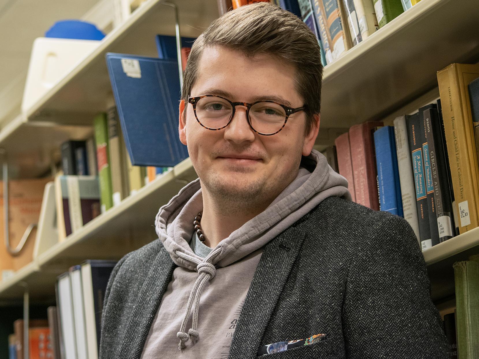Logan Daly in front of library shelves