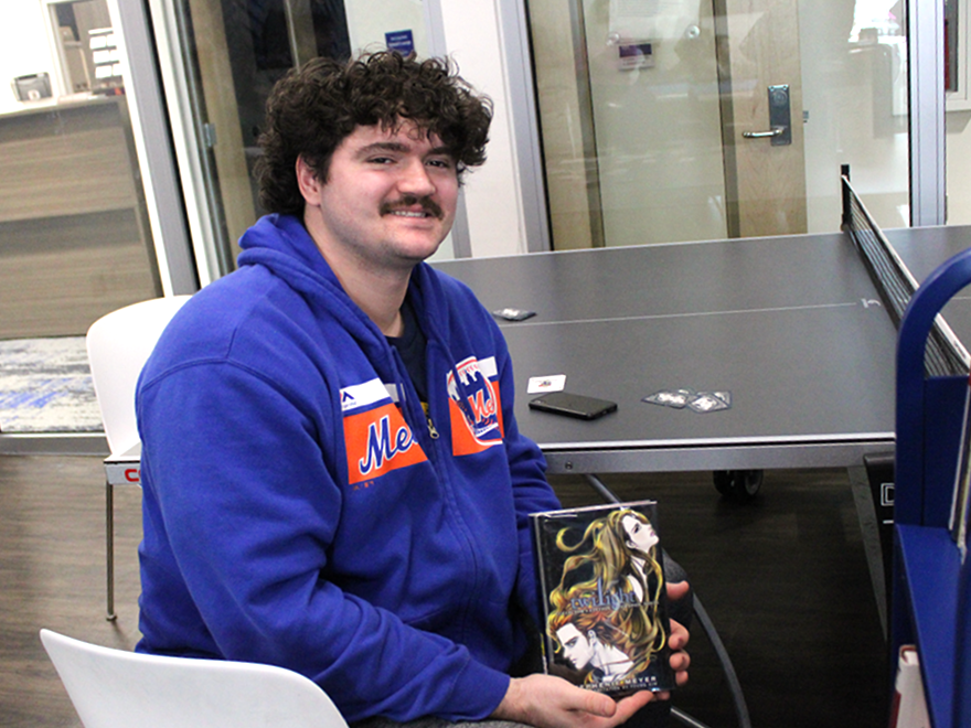 Student Matthew Coggins shows off his book selection from this month's roving Library Cart.