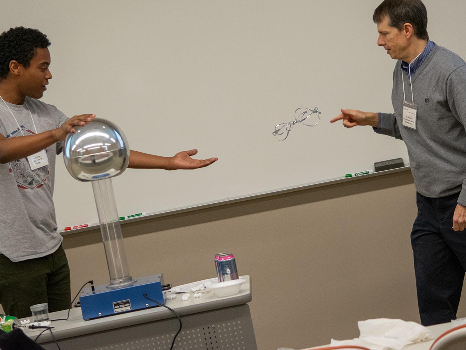 A student and professor do an experiment with an electrostatic generator