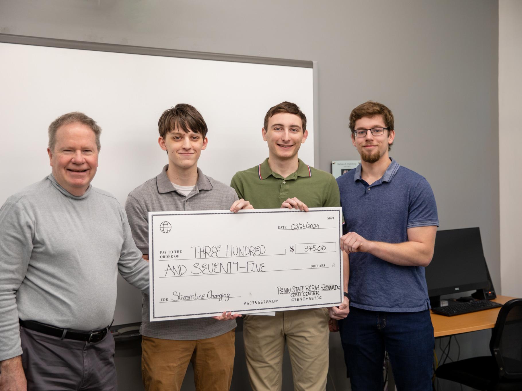 Male students pose for photo with $375 check