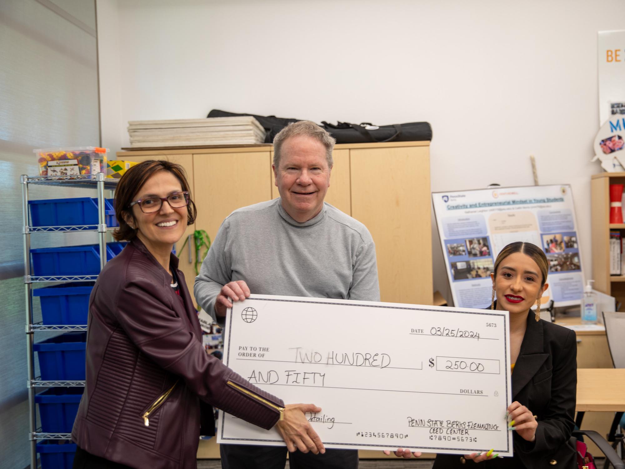 Student poses for photo with check of $250