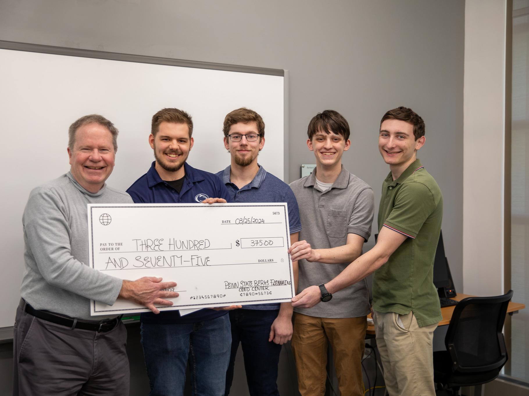 Group of male students pose for photo with $375 check
