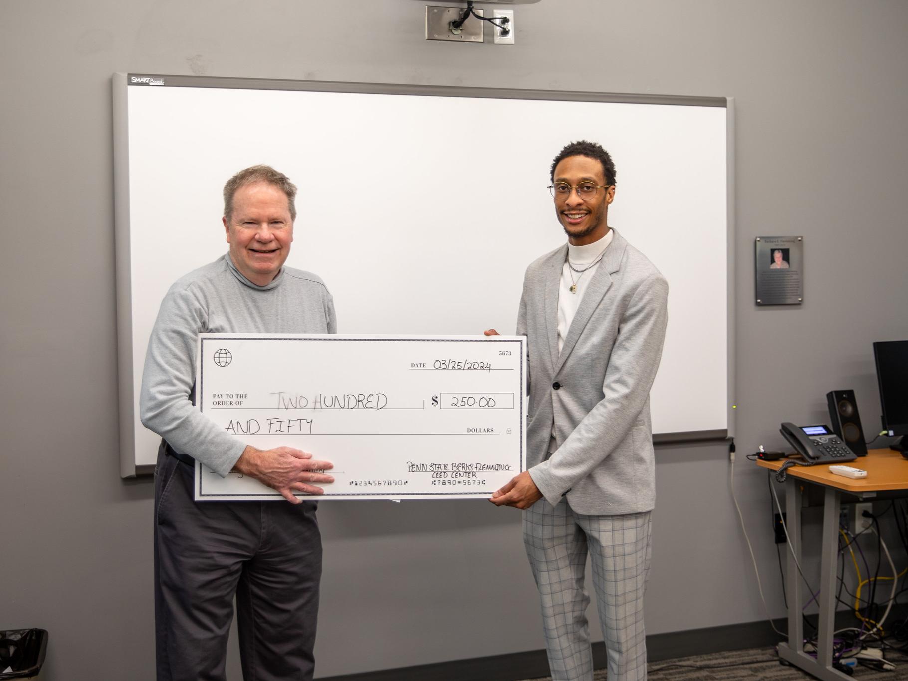 Male student poses with check of $250