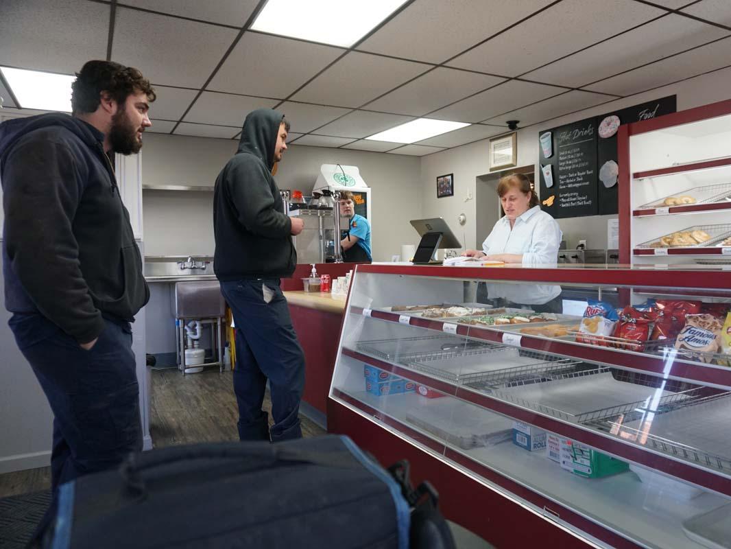 Customers ordering breakfast at a counter inside a restaurant.