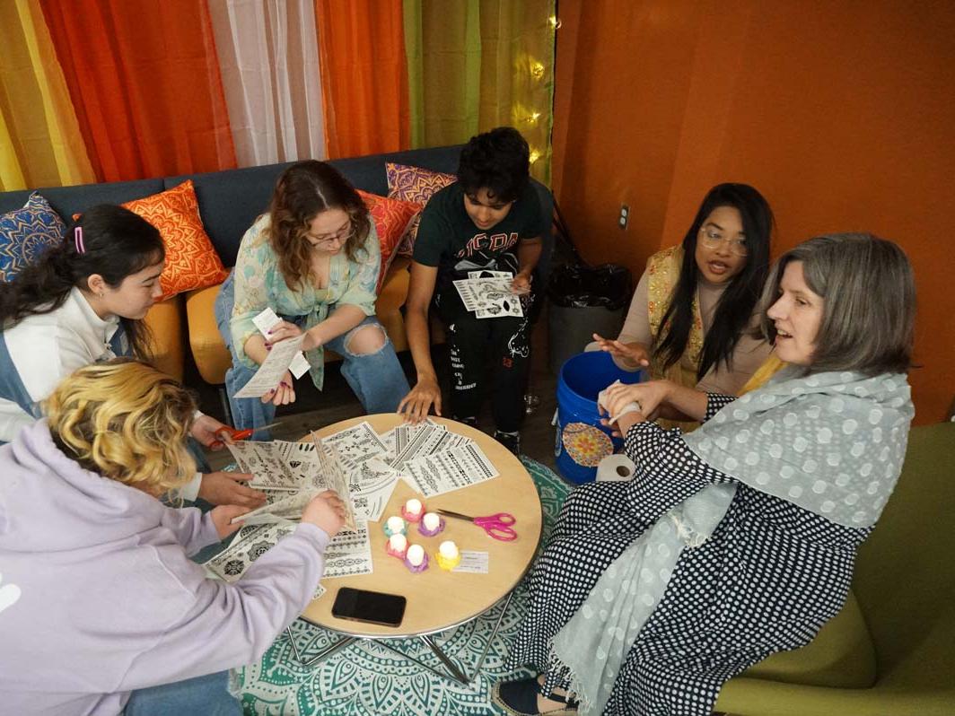 Students sitting in a circle around a table doing arts and crafts.