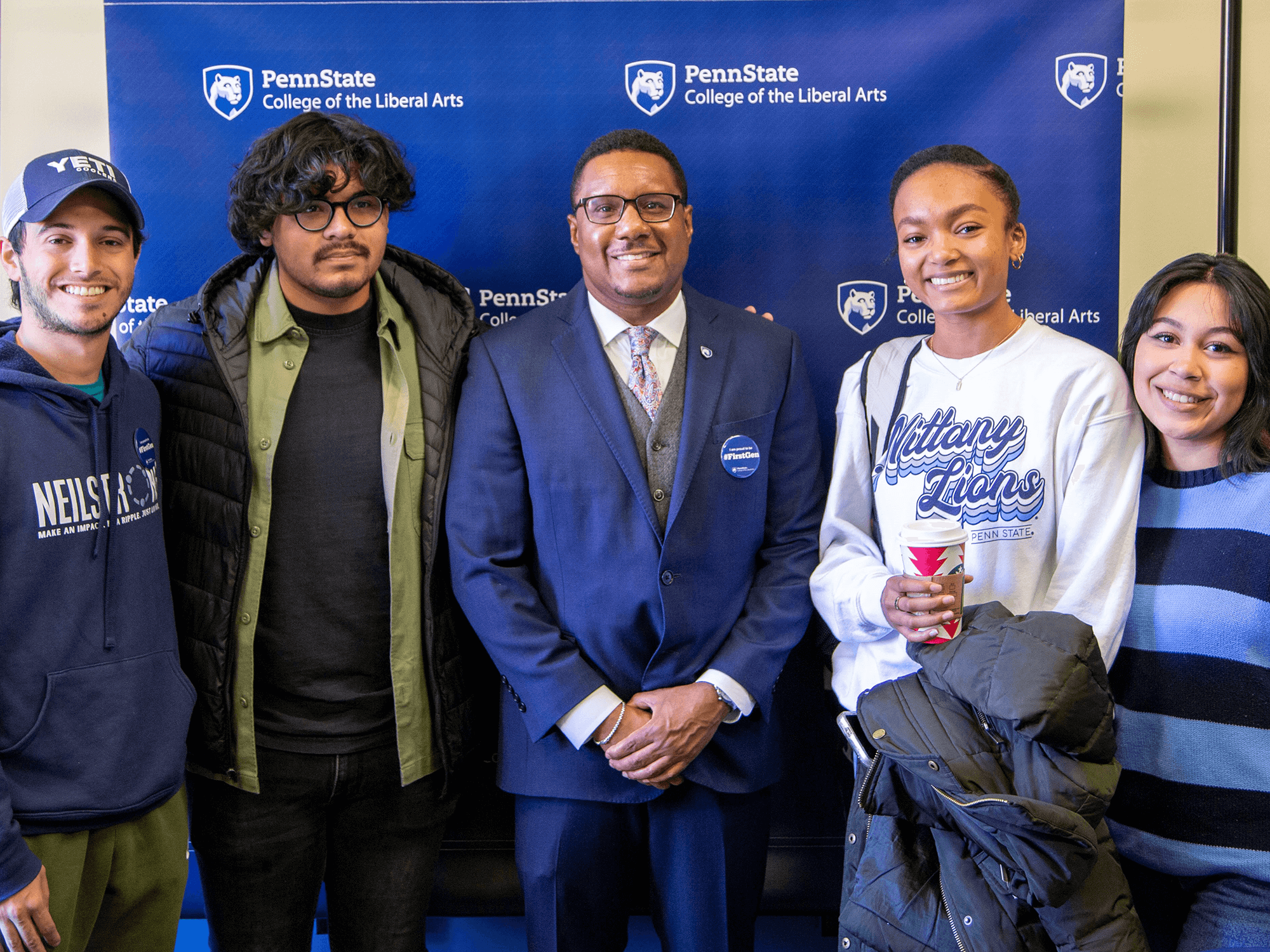 Four Liberal Arts students pose with Dean Lang (center) in front of a College of the Liberal Arts backdrop in the Chaiken Center during the Liberal Arts First-Gen Celebration on Nov. 8, 2022.