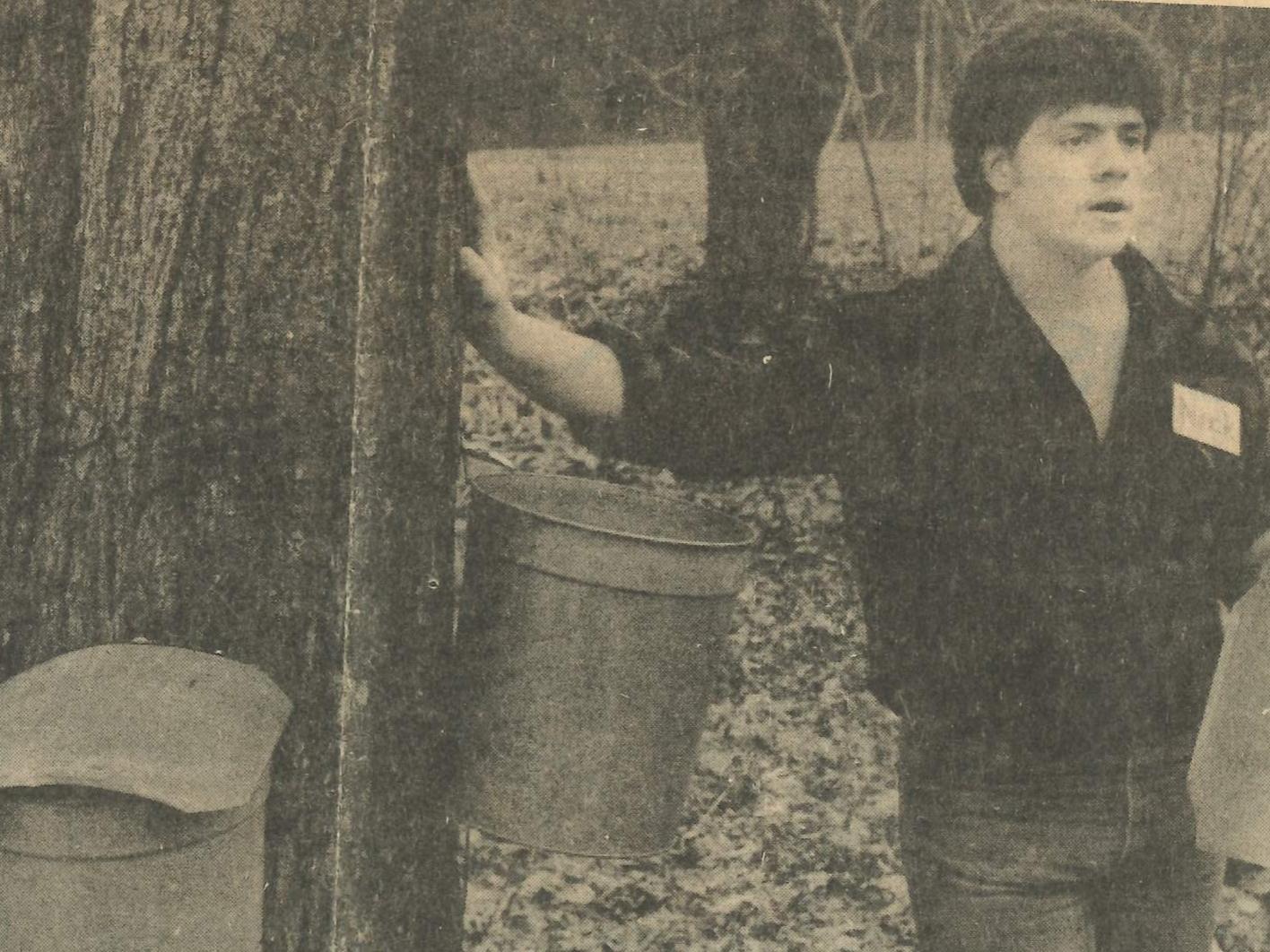 Black-and-white newspaper photo of maple tree with sap buckets and interpreter at 1984 Maple Harvest Festival