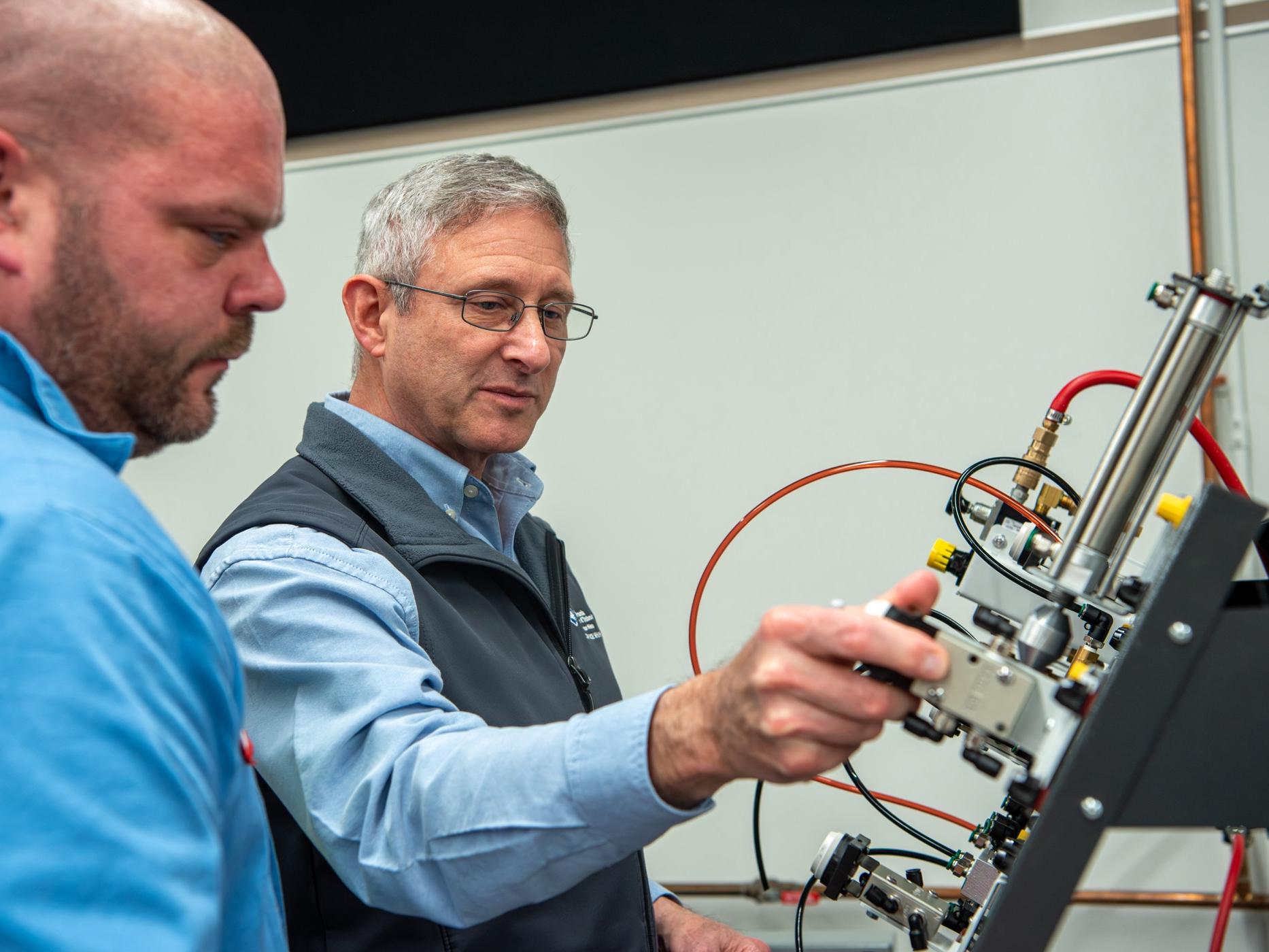 One person shows another how to use a piece of equipment.