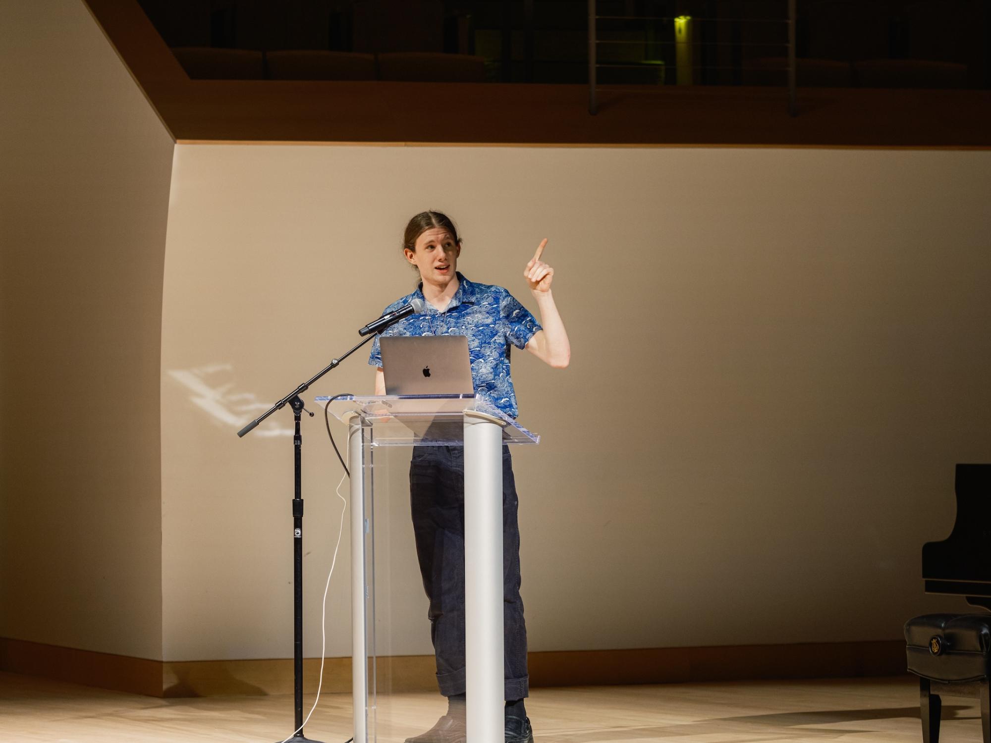 Zachary McKee presenting from behind podium in Recital Hall