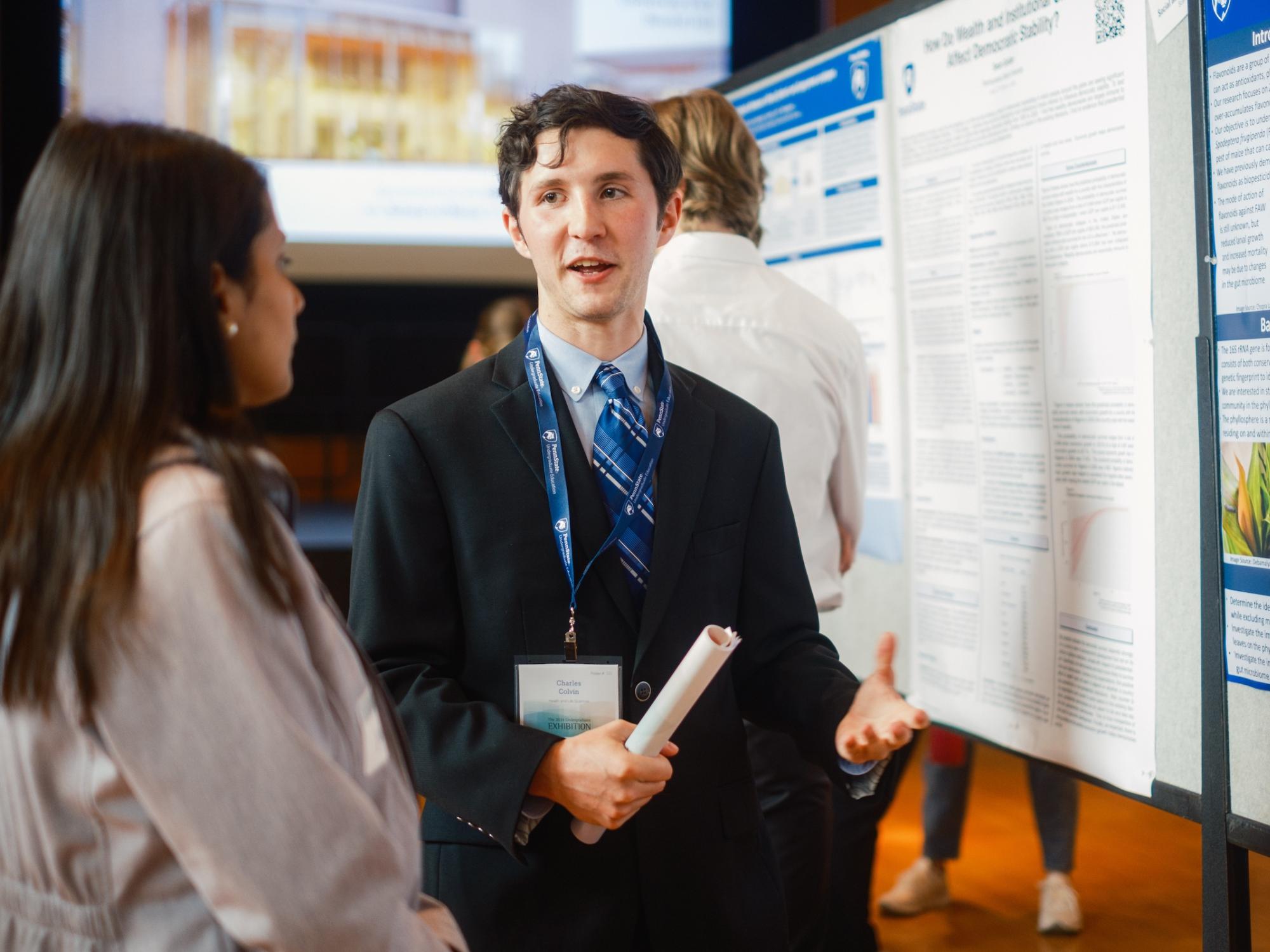 Charles Colvin talking to judge in front of his research poster