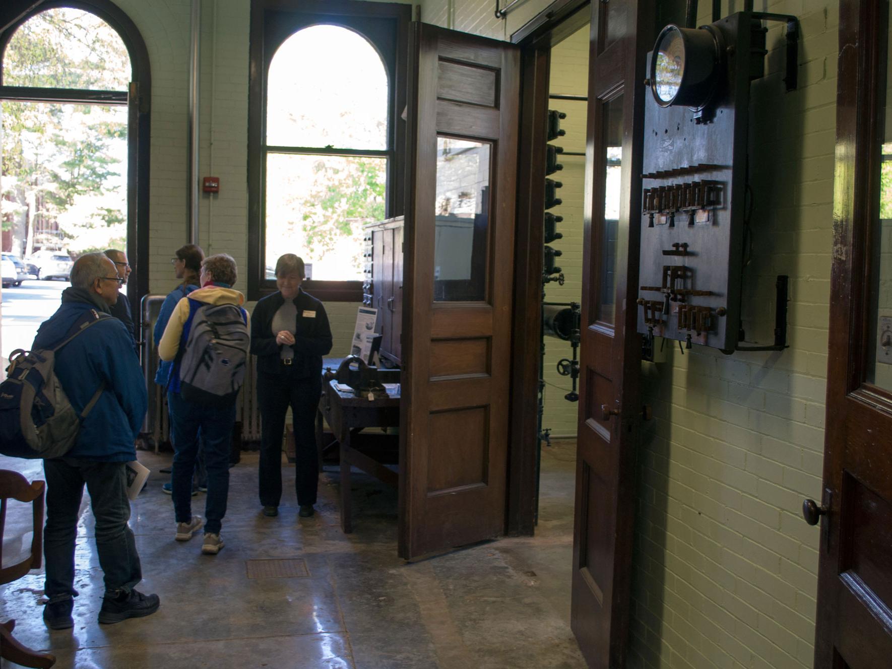 The foyer of the Armsby Respiration Calorimeter Museum, a brick building with cement floors, full of visitors.