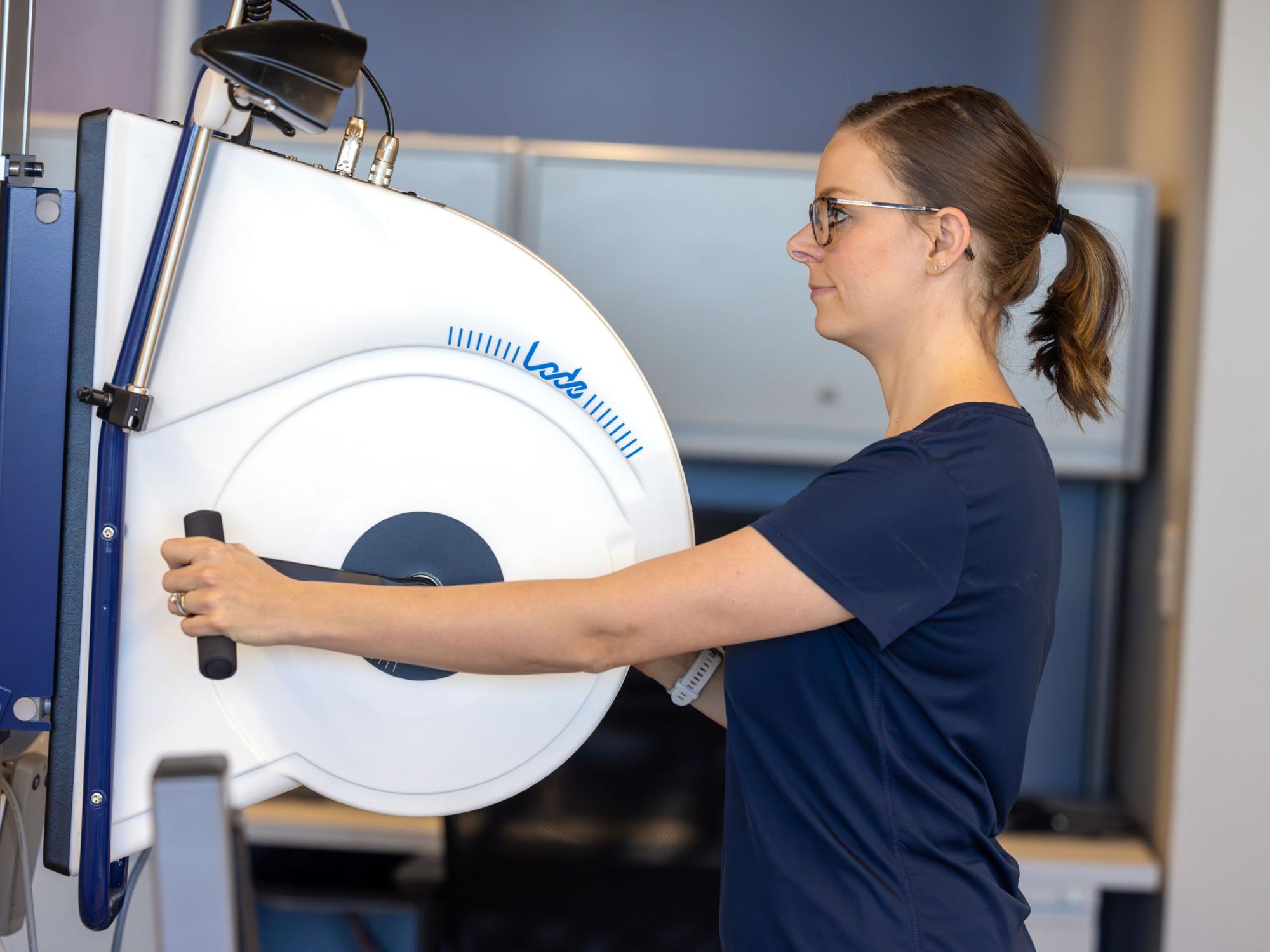 A patient uses the arm ergometer to exercise her upper body
