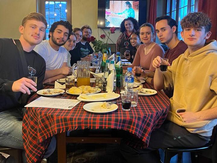 Penn State students sit around a table while eating and drinking in Georgia.