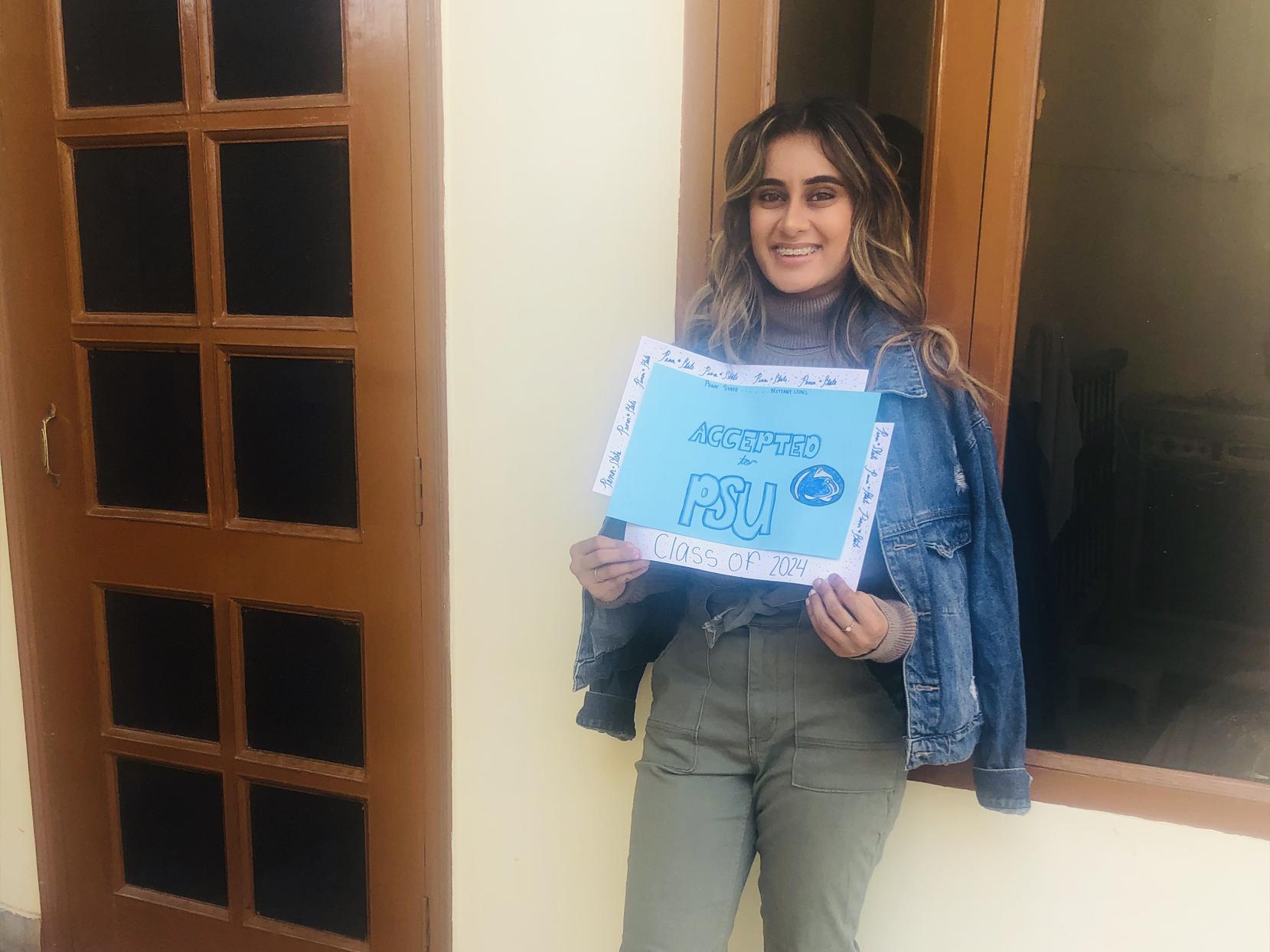 Gurleen Grewal holds a sign saying she was accepted to Penn State