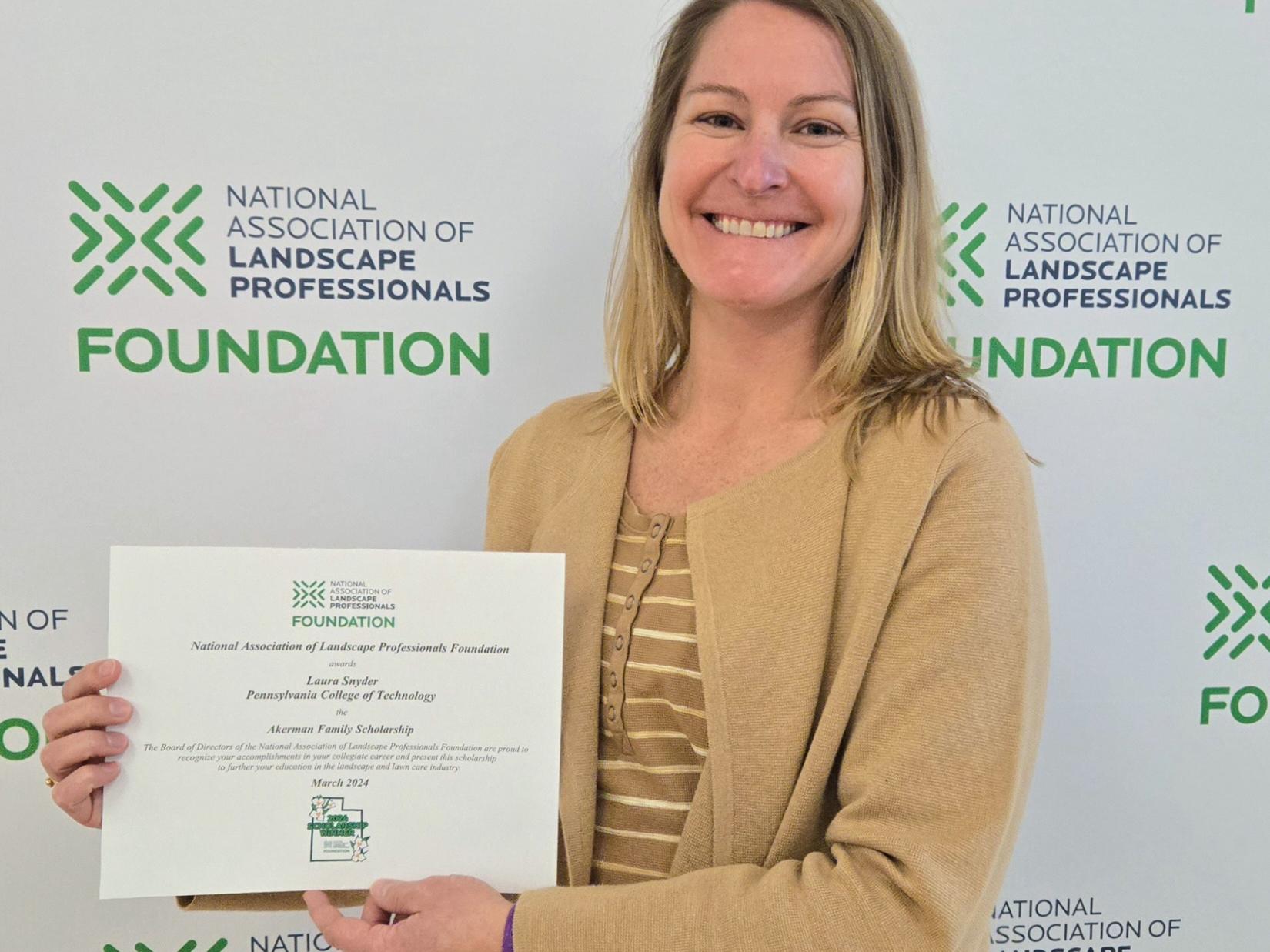 Laura Snyder holds up a certificate