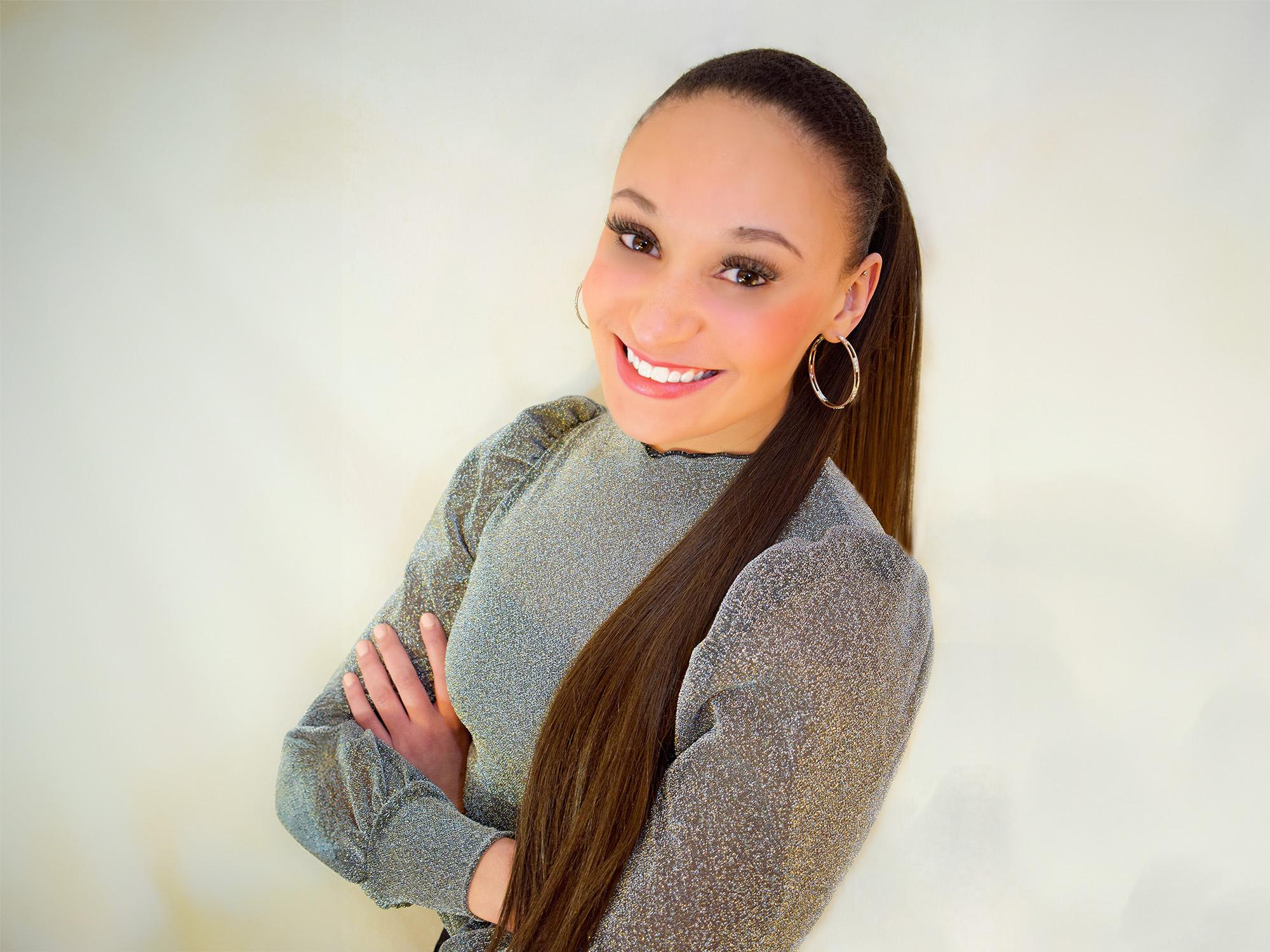 Mia Jordan in a silver sparkly dress in front of a white wall